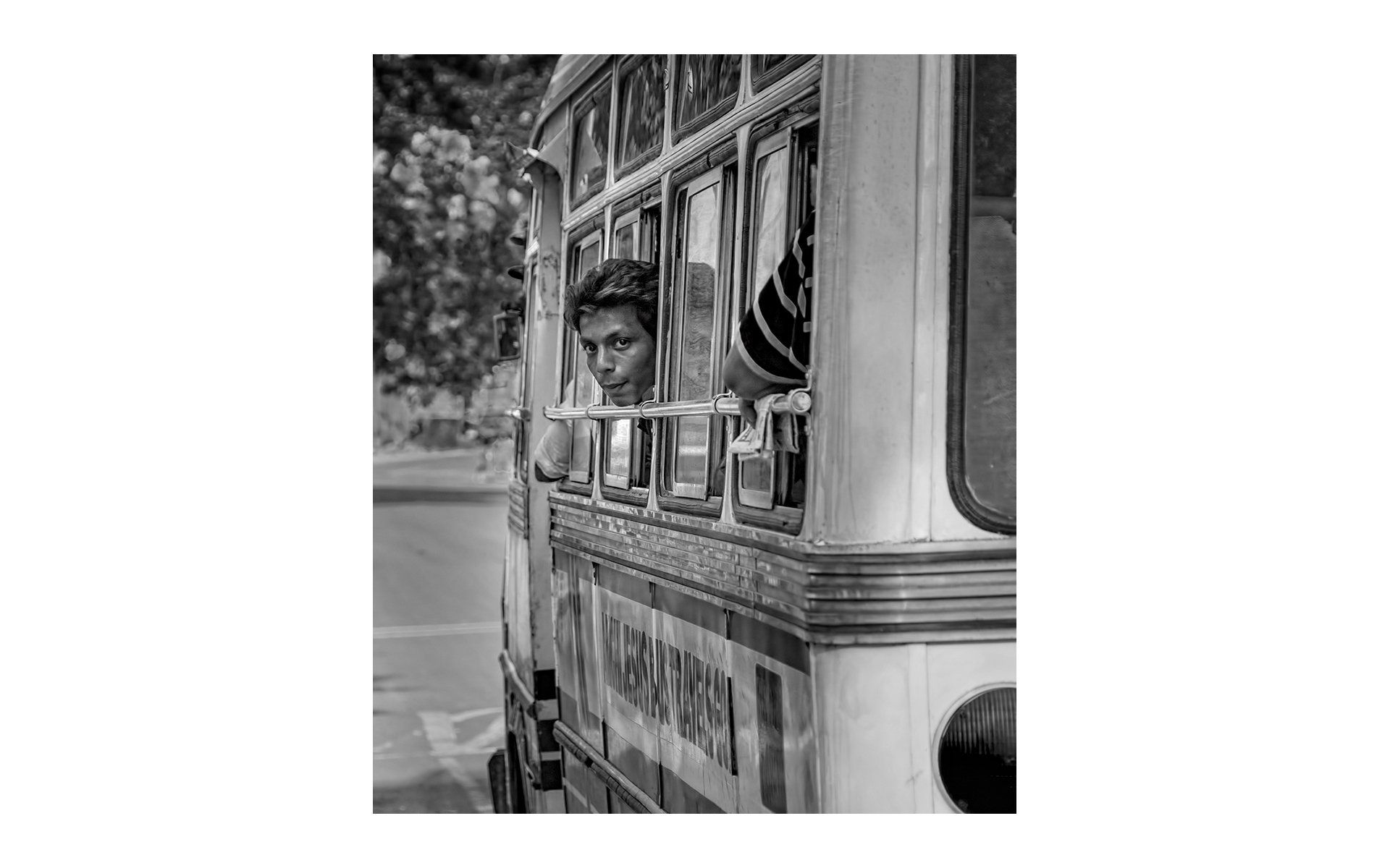 a young man looking back from a bus window