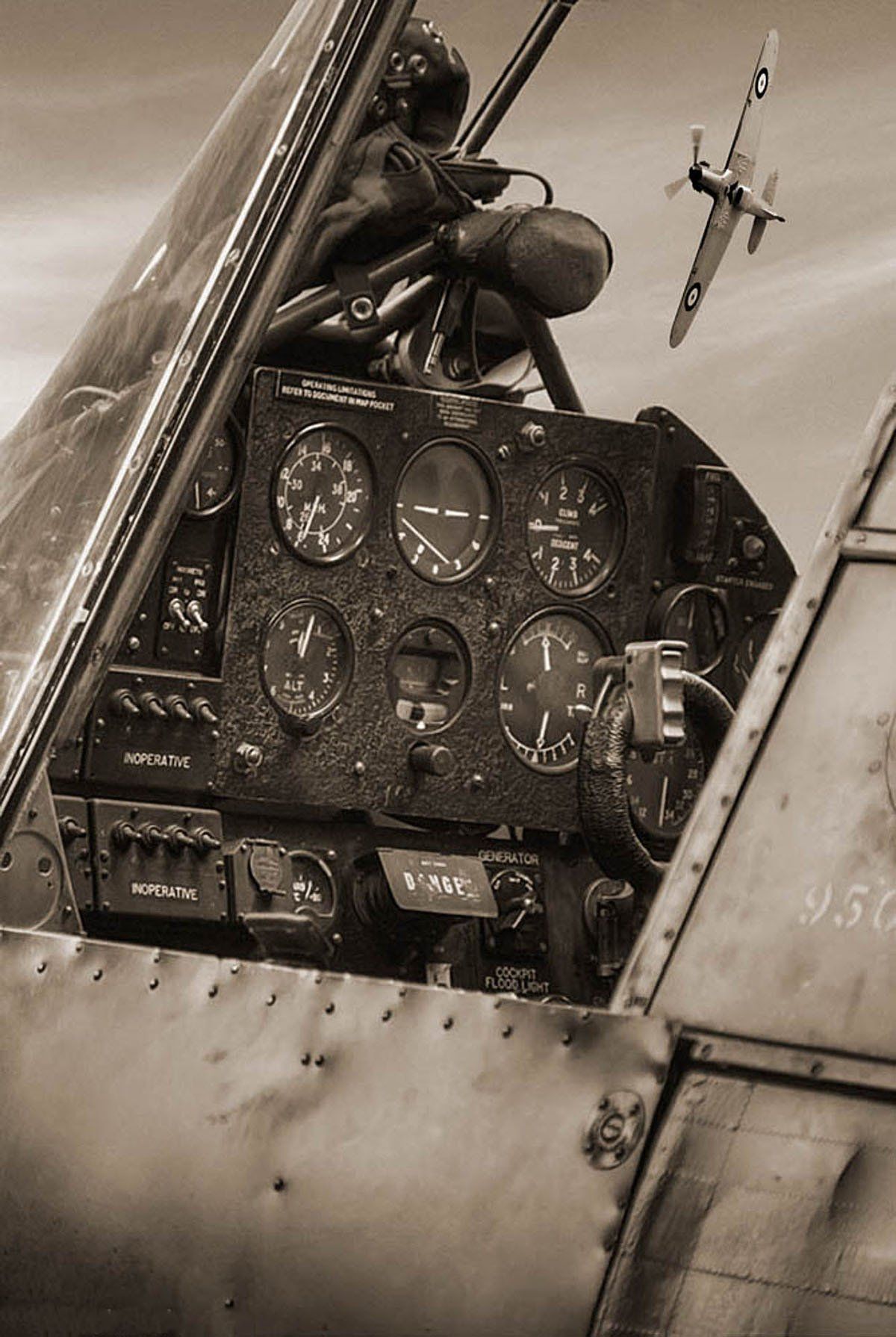 an aircraft cockpit, with a spitfire in the sky above