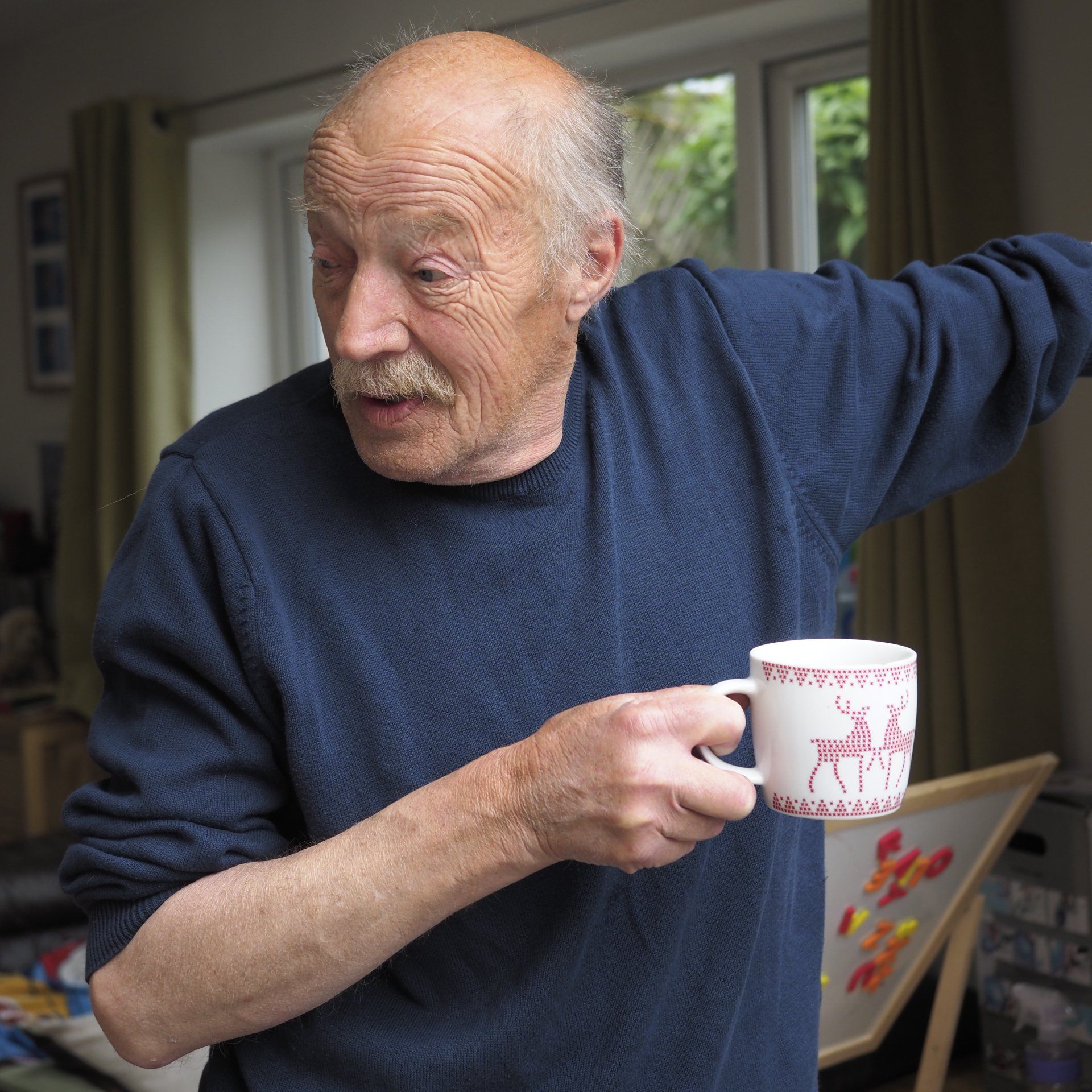 an older man with a mug of coffee in a doorway