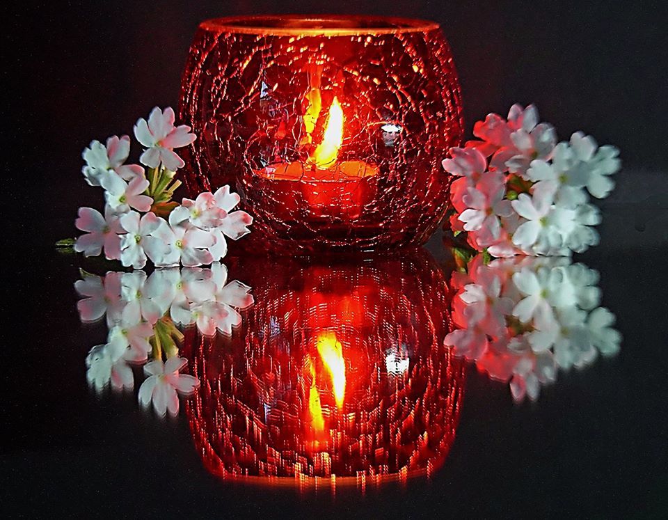 Photo by: Graham Elvidge a lit candle in a jar on a reflective surface