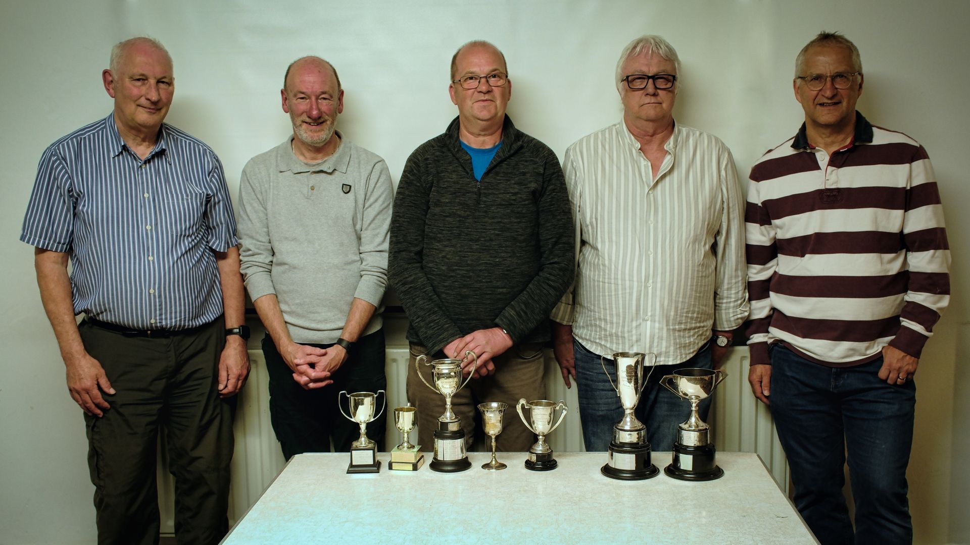 Trophy, and cups presentation photography club members beside the trophies, and cups for presentation