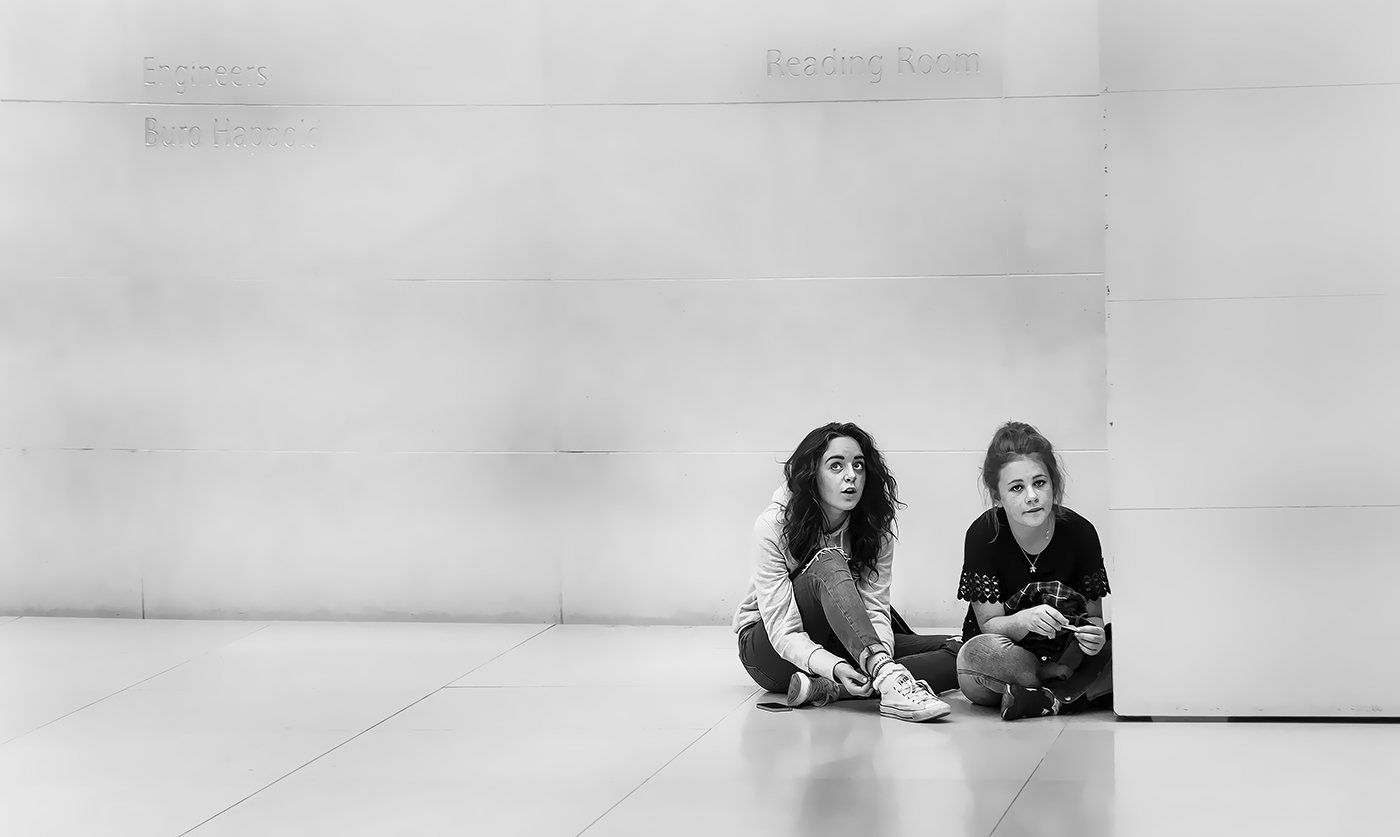 two girls sitting on the floor of a gallery