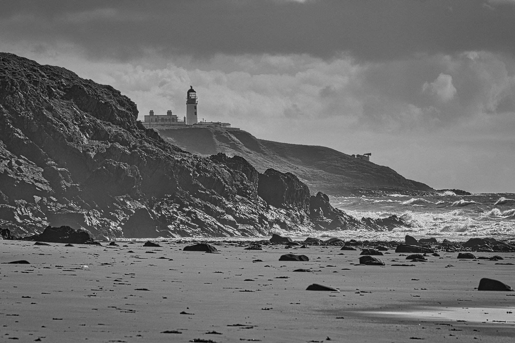 a lighthouse on the rocks above the beach