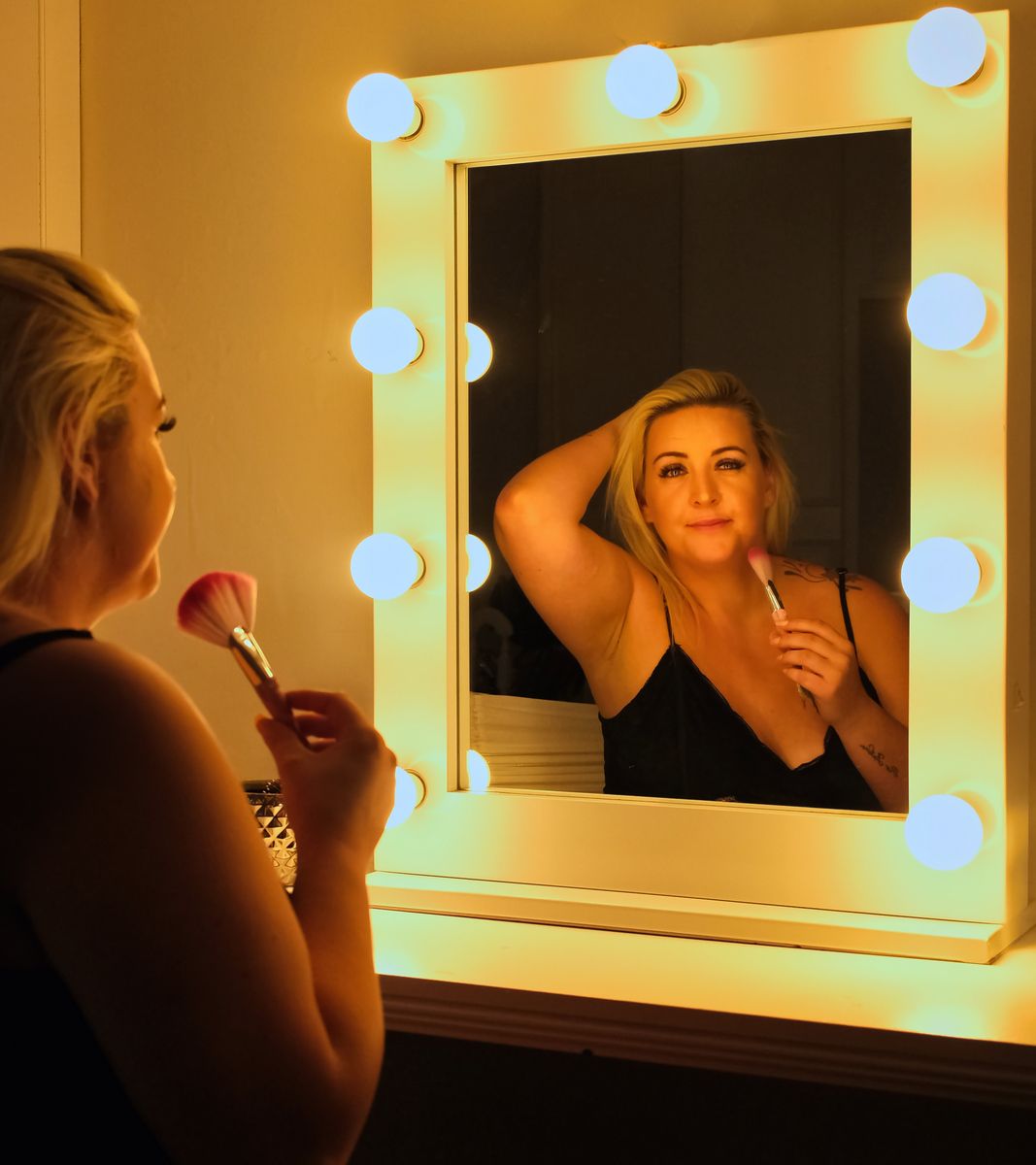 A view of a woman in a mirror putting on makeup