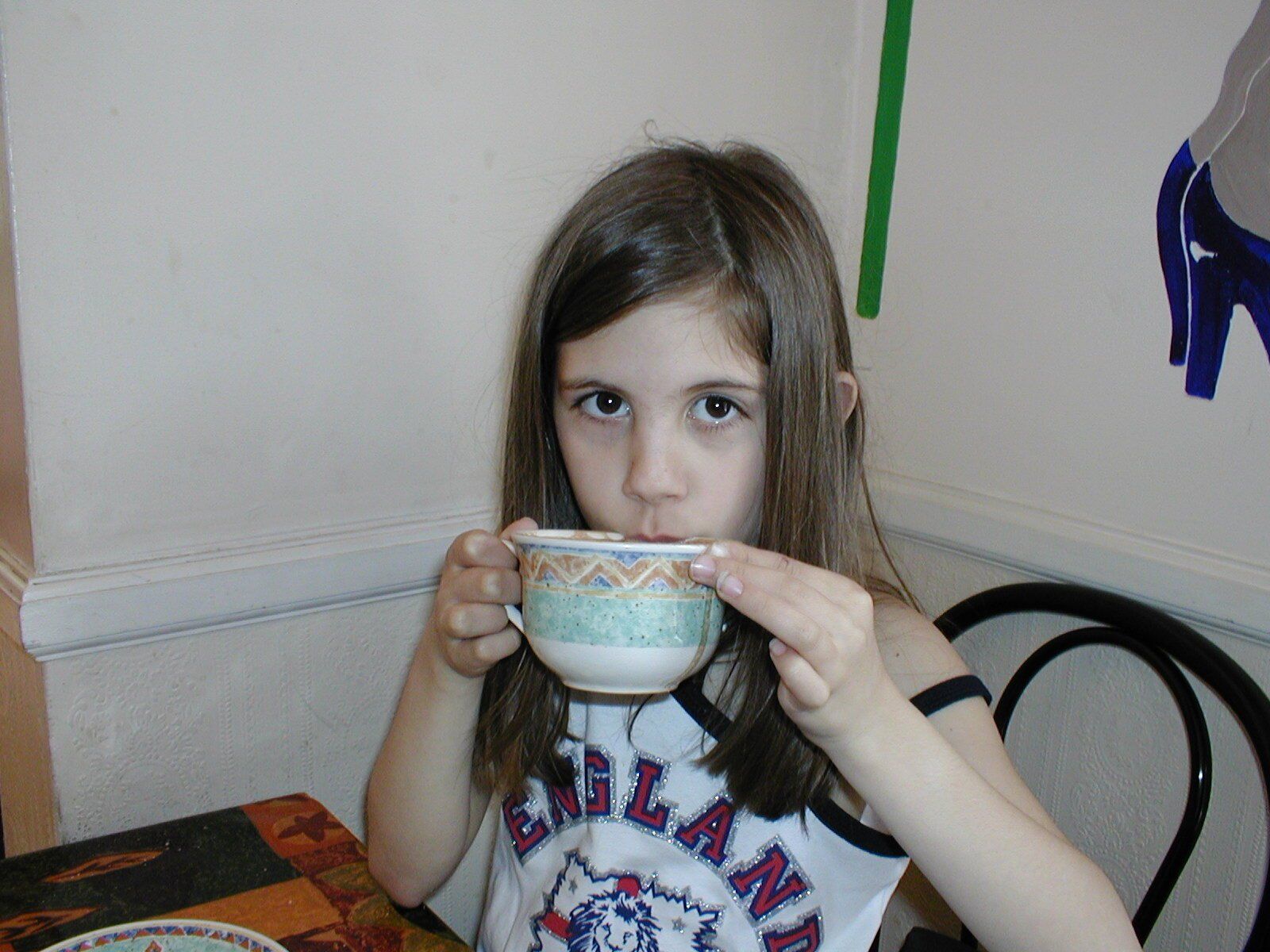 a young girl drinking a large mug of hot chocolate