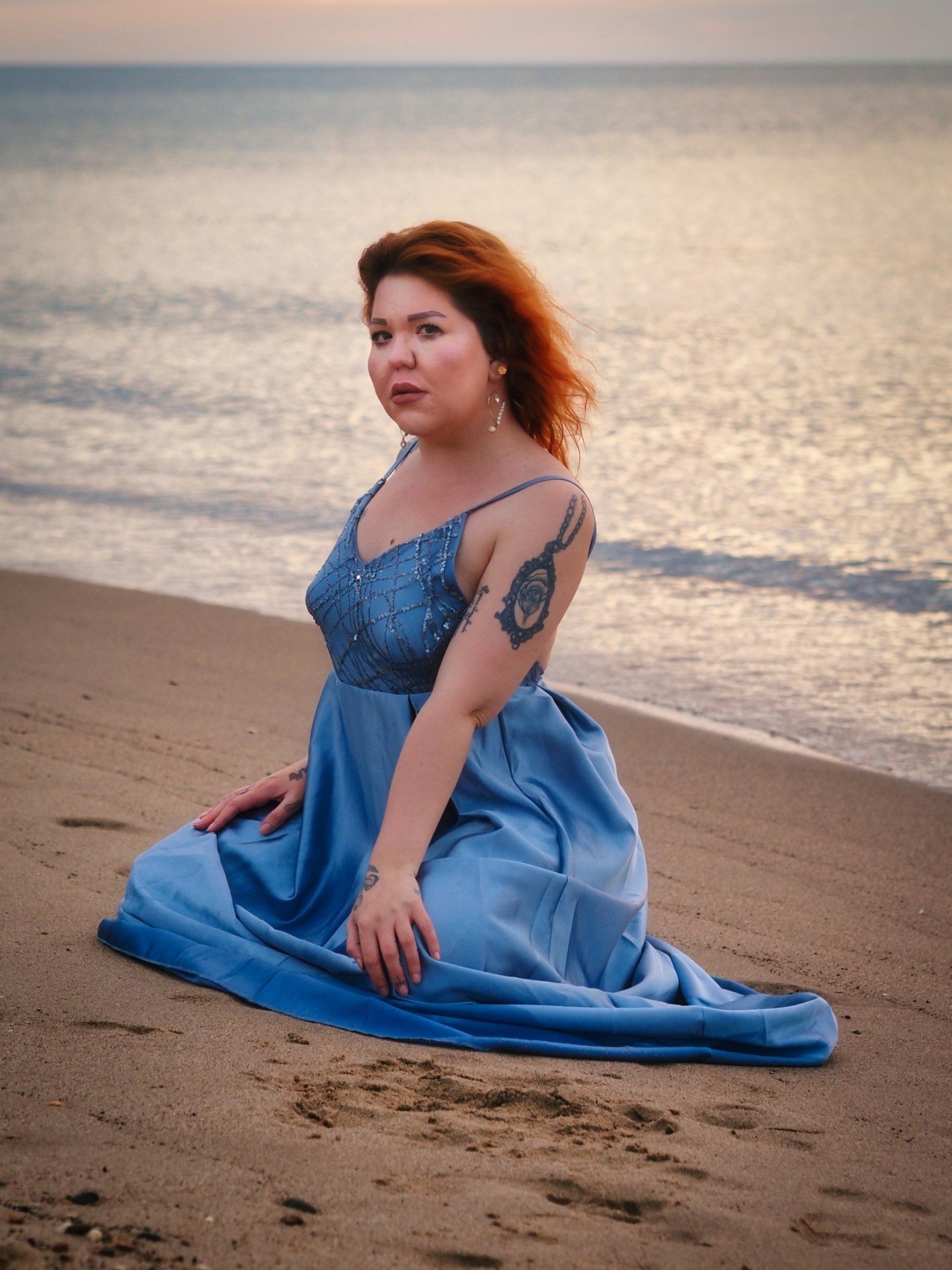 a young lady posing on a beach at sunrise