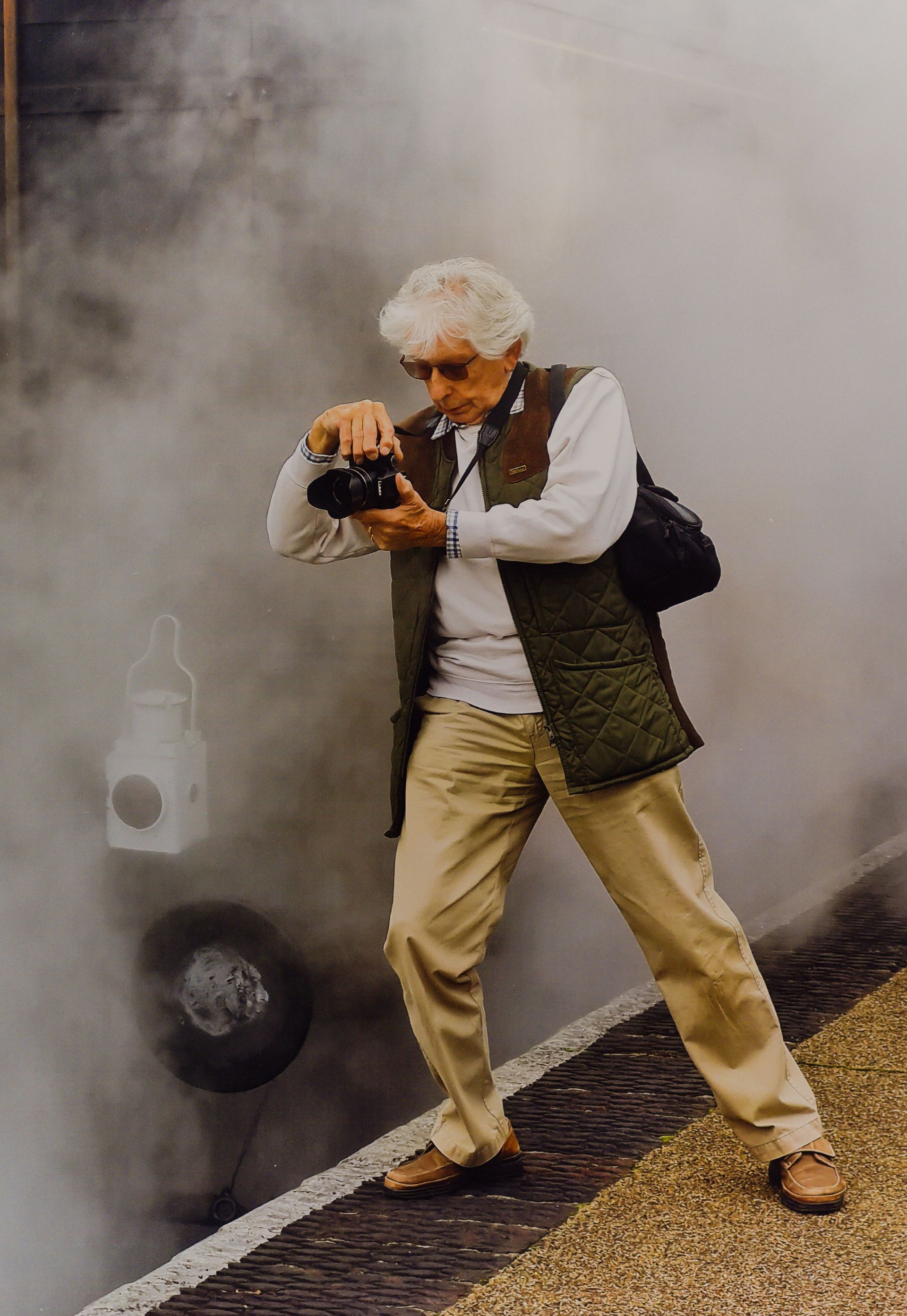A photographer surrounded by steam from a steam locomotive