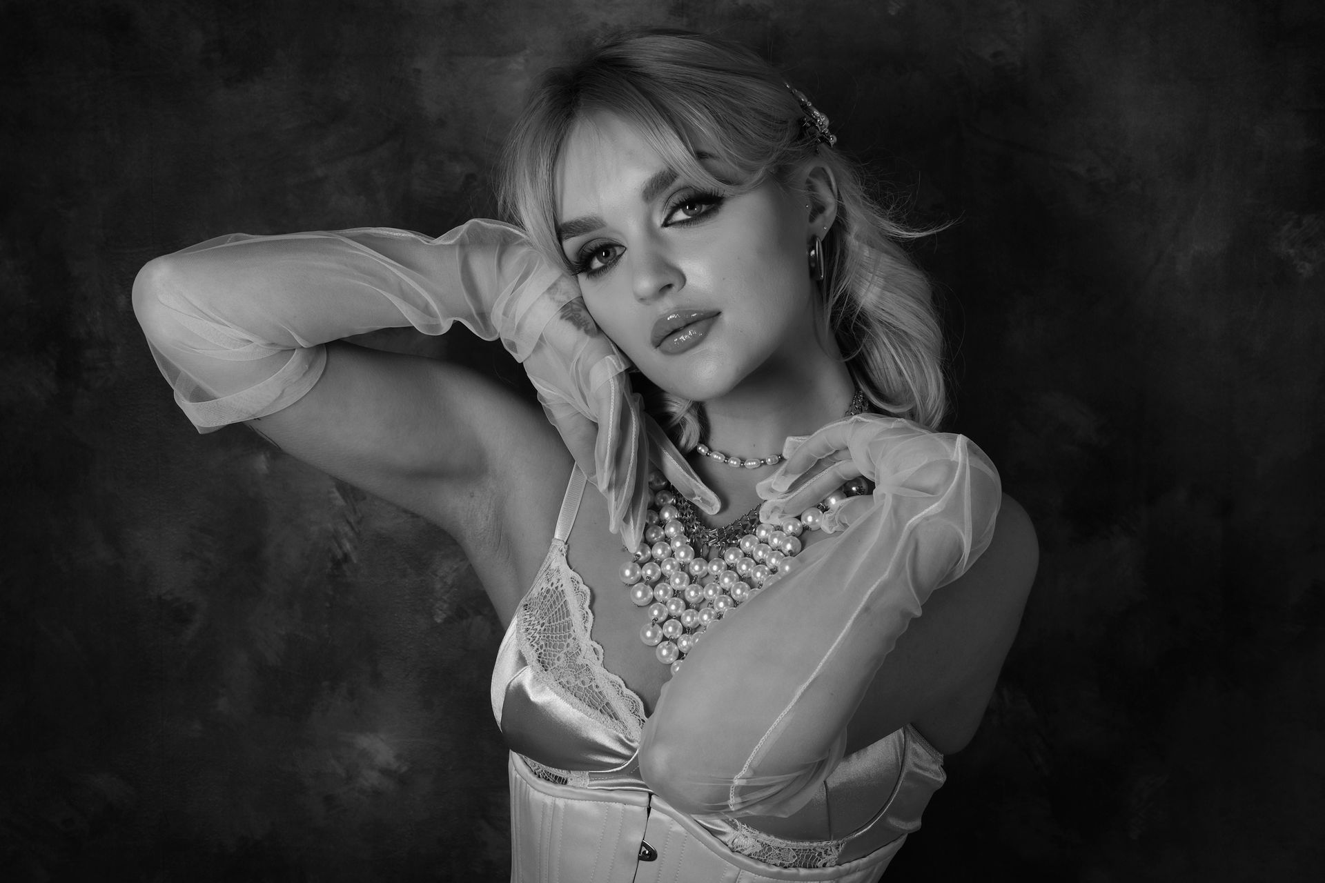 A monochrome studio portrait of a female model wearing pearls