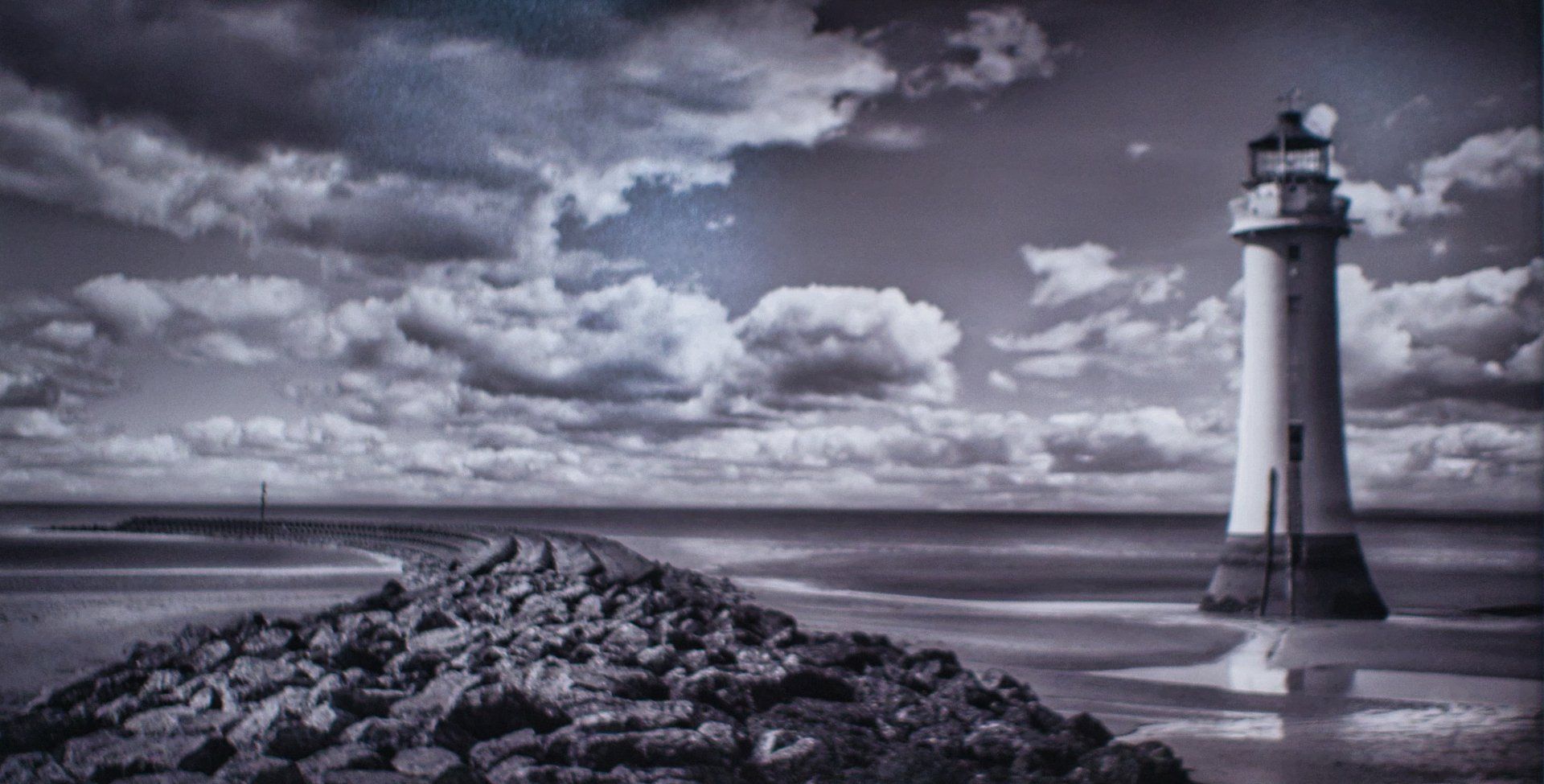 a lighthouse on a rock viewed from the beach