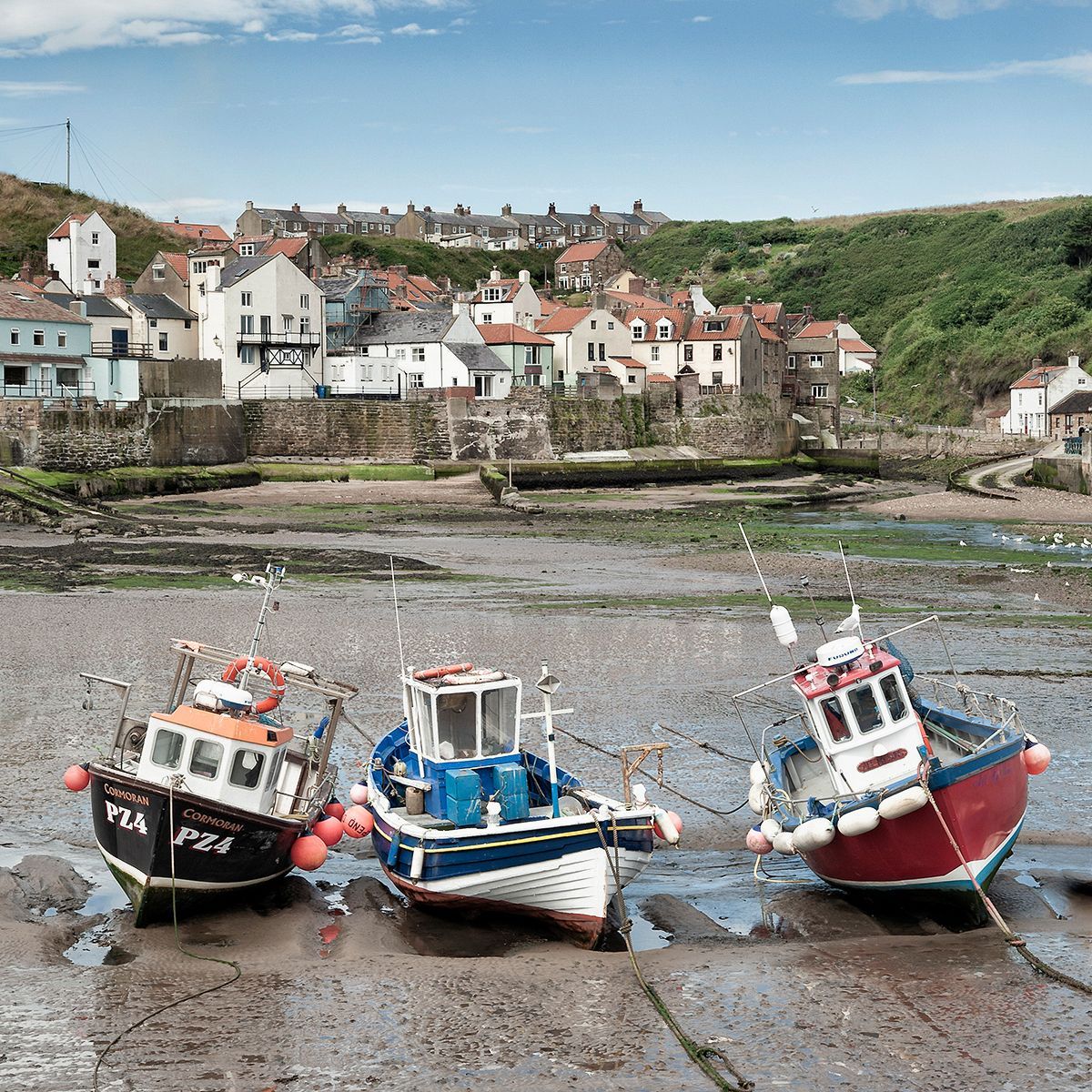 A view of three boats at low tide Staithes