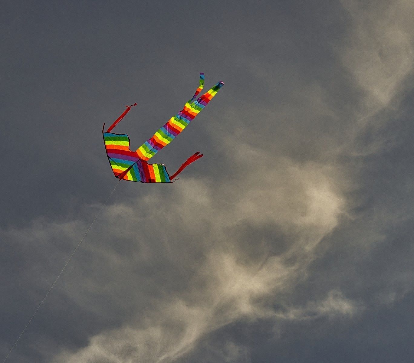 a bright kite flown against an angry summer sky