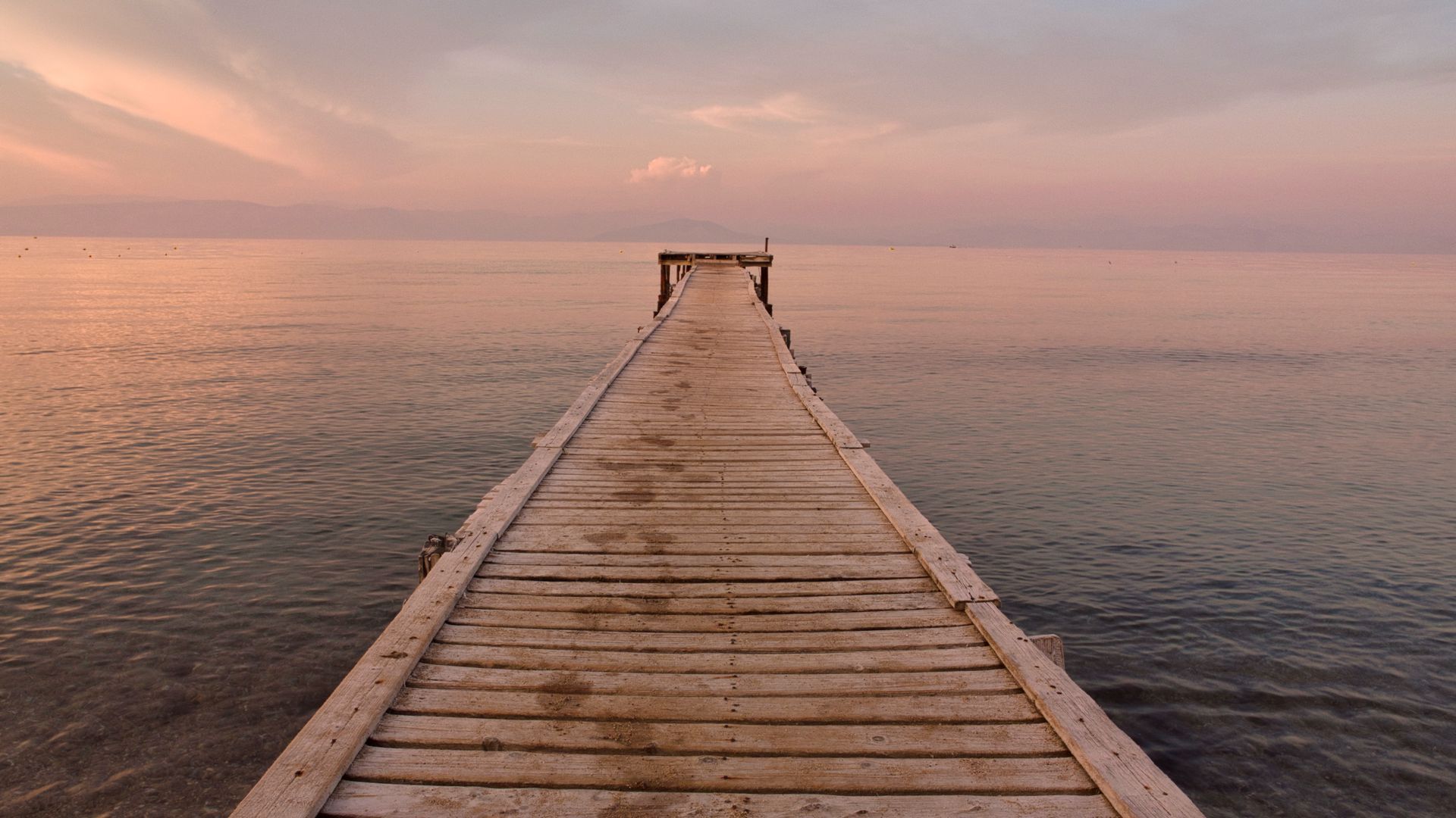 A view of a wooden jetty in Corfu at sunset