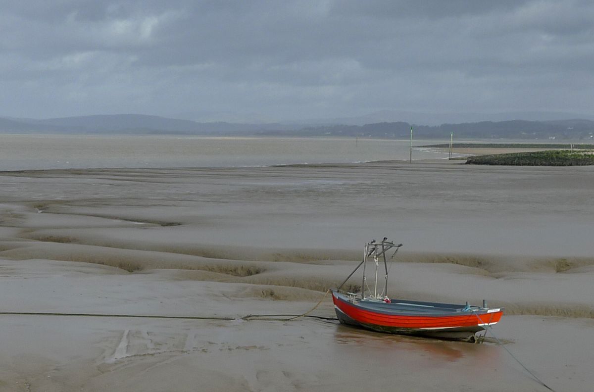 A red boat beached on mud flats