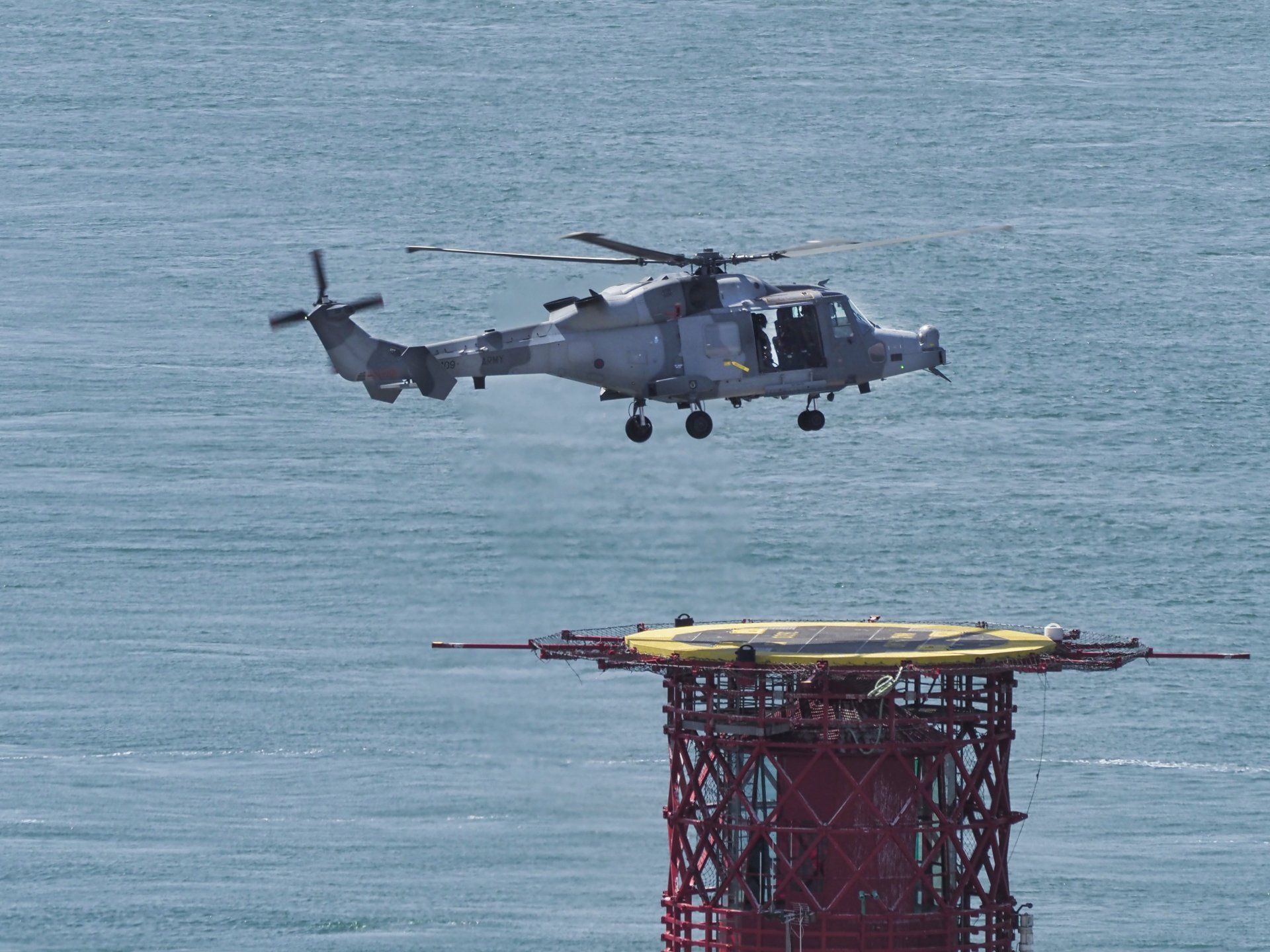 Augusta Westland Wildcat ZZ409 by Derek Smith a helicopter hovering over a helipad