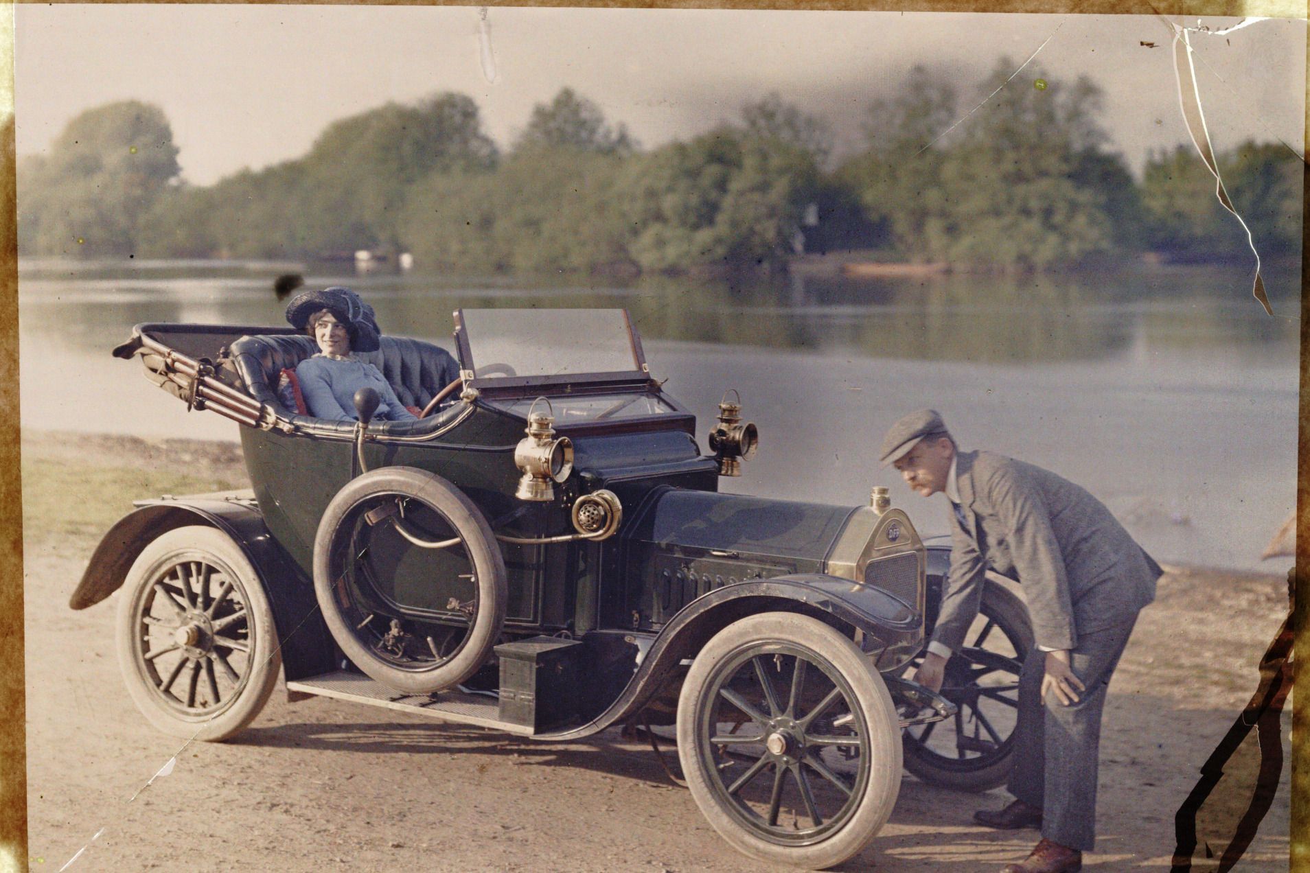 a man with a starting handle cranking up a vintage car