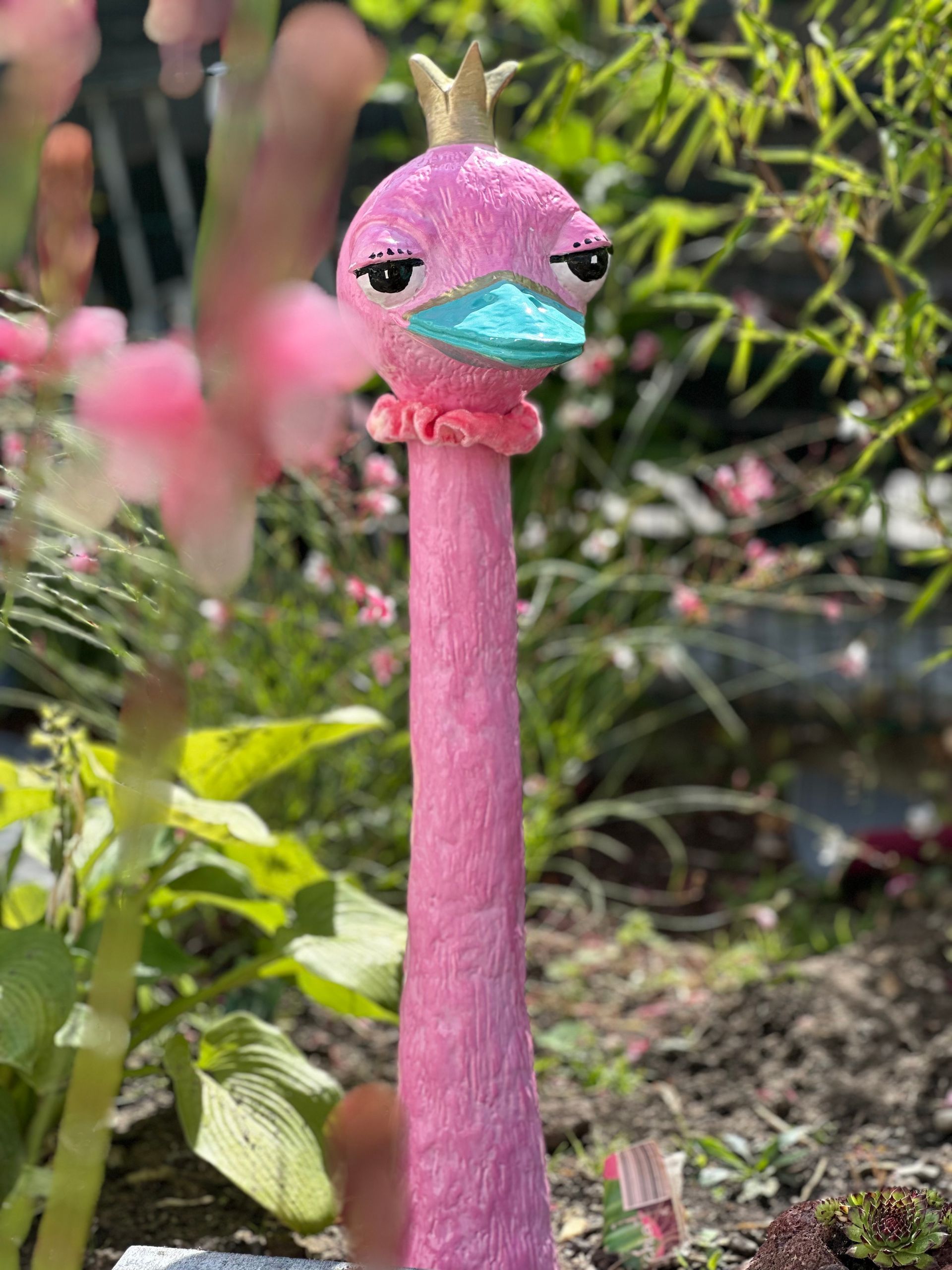 Pinke Flamingo-Figur mit Krone und Maske im Praxisgarten der CITYPRAXIS HAHNE