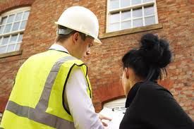 Man in white hard hat and high vis showing a lady a document