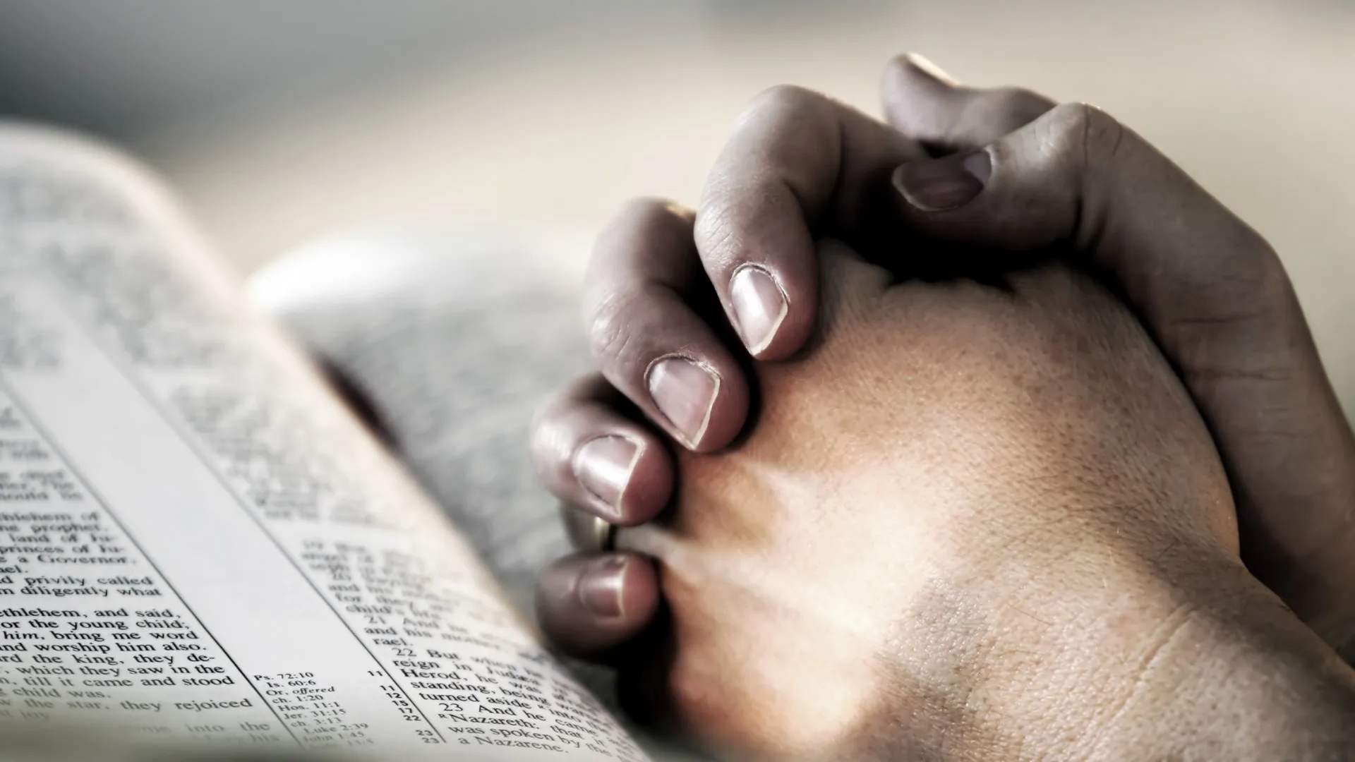 Picture of hands clasped over open bible.