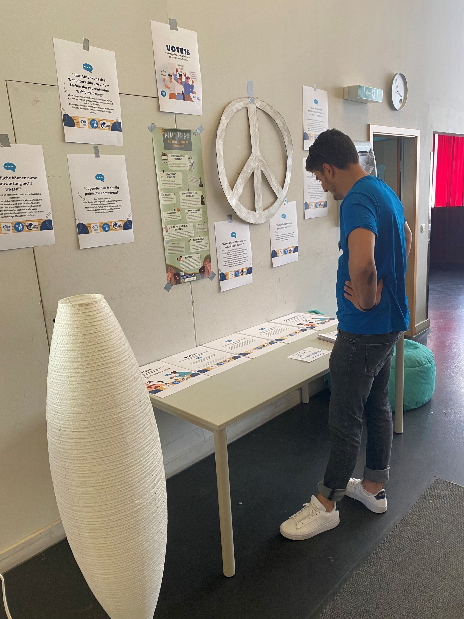 Lange Nacht der Demokratie. Ein junger Mann steht vor einem Infotisch und schaut sich die ausgelegten Flyer an.