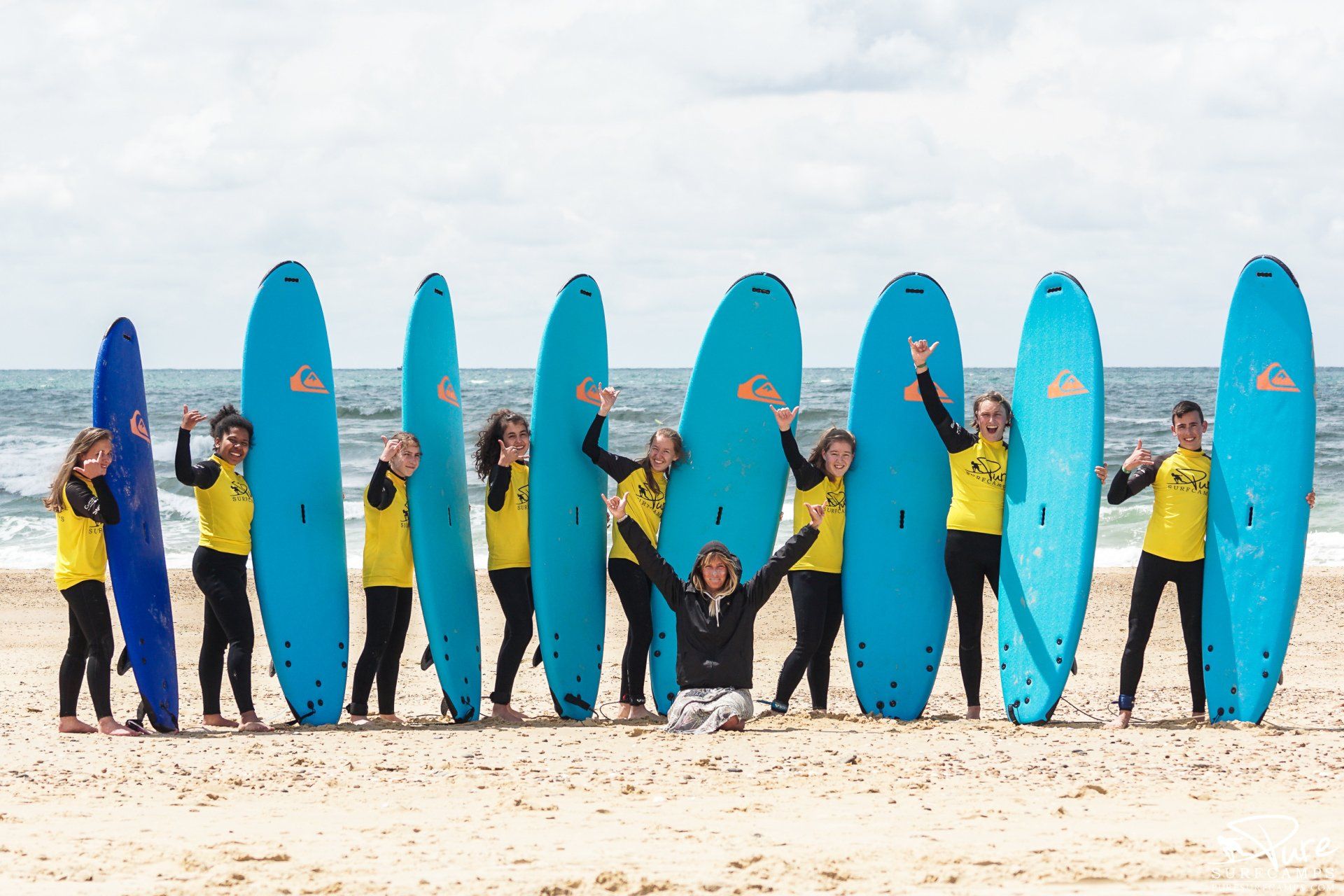 Junge Menschen posieren vor blauen Surfbrettern