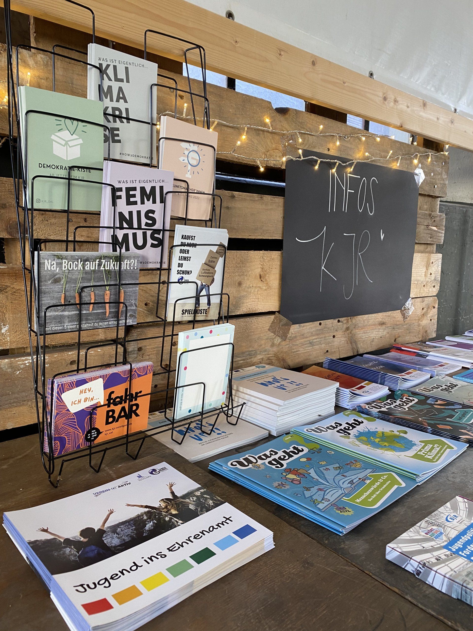 Flyer liegen vor einer Holzwand aus.