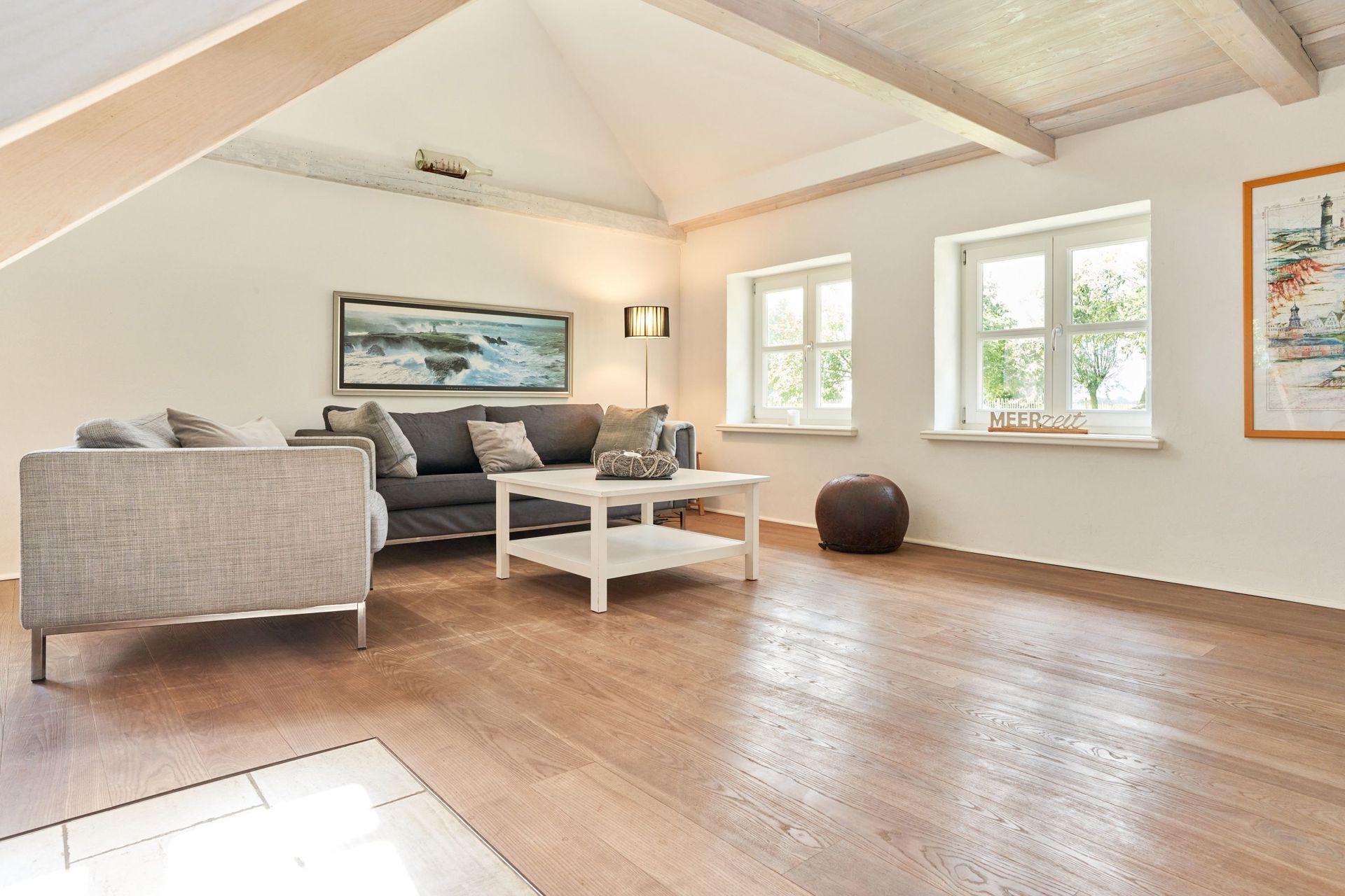 Gemütliche Sitzecke im Haubarg-Kieker mit komfortablem Sofa und Sessel – ideal für entspannte Lesestunden unter dem Reetdach.