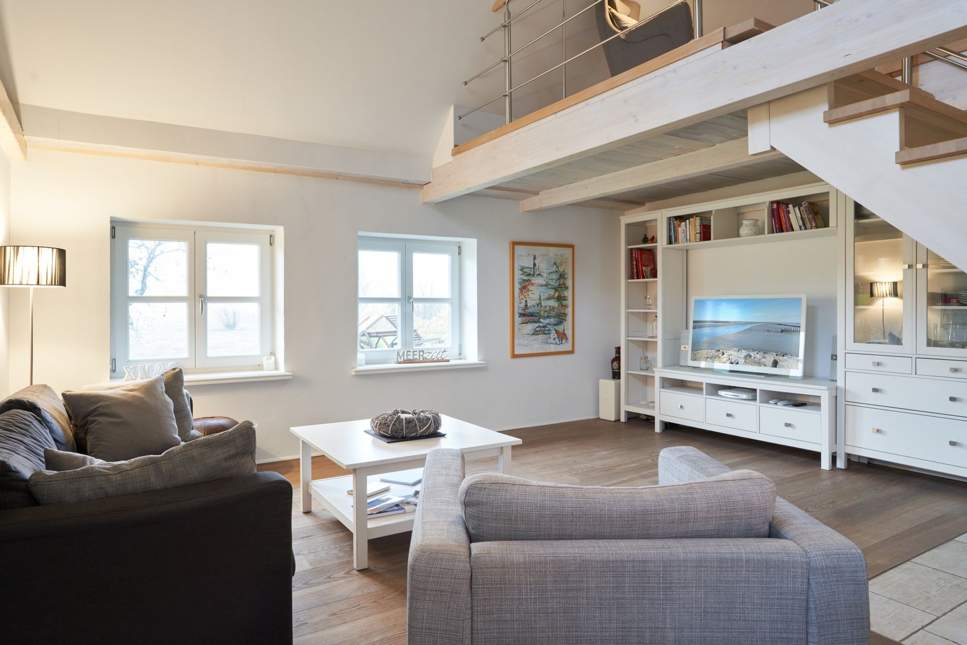 Gemütliche Sitzecke im Haubarg-Kieker mit komfortablem Sofa und Sessel – ideal für entspannte Lesestunden unter dem Reetdach.