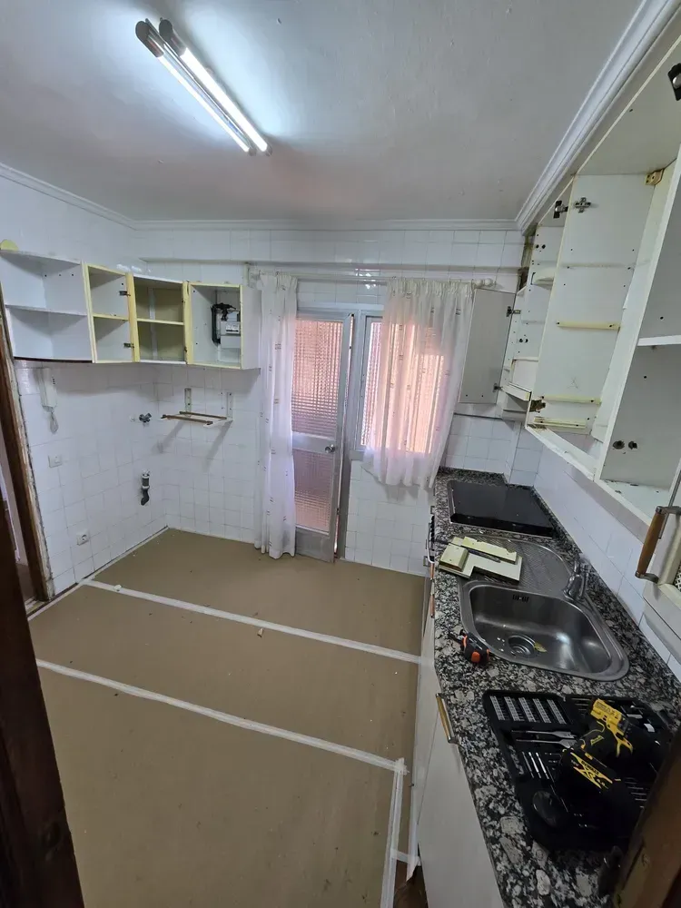 Zona de cocina protegida con cartón técnico y mobiliario desmontado durante reforma en Madrid 1