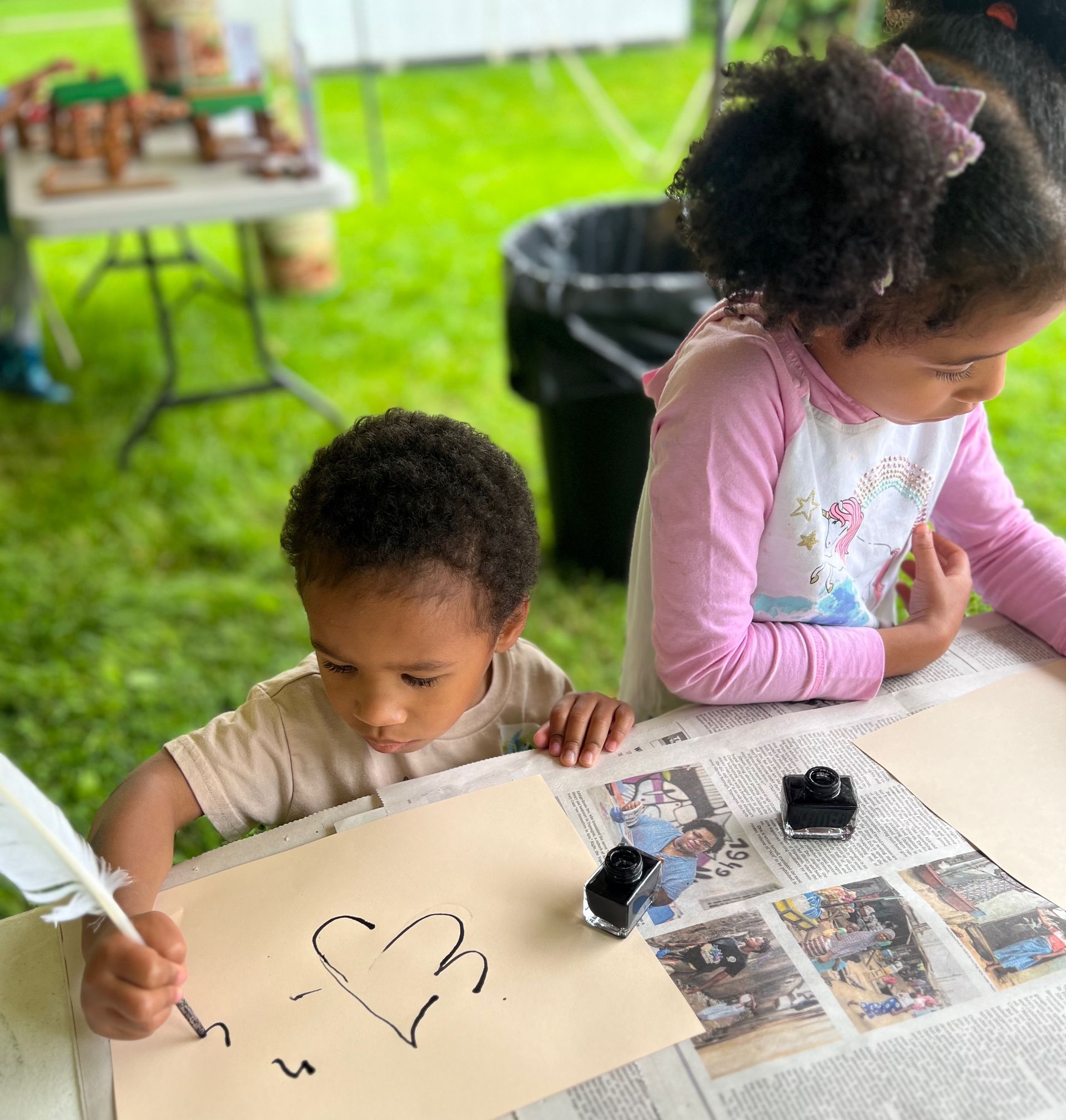 two young children writing with a quill