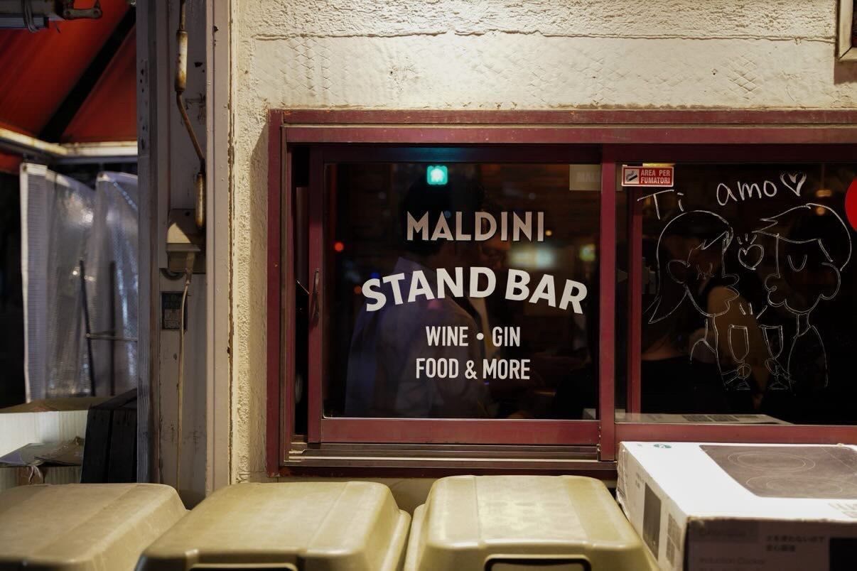 Hand painted signage, logo, and menu items on sliding glass window. White oil based enamel paint. Painted on bar window