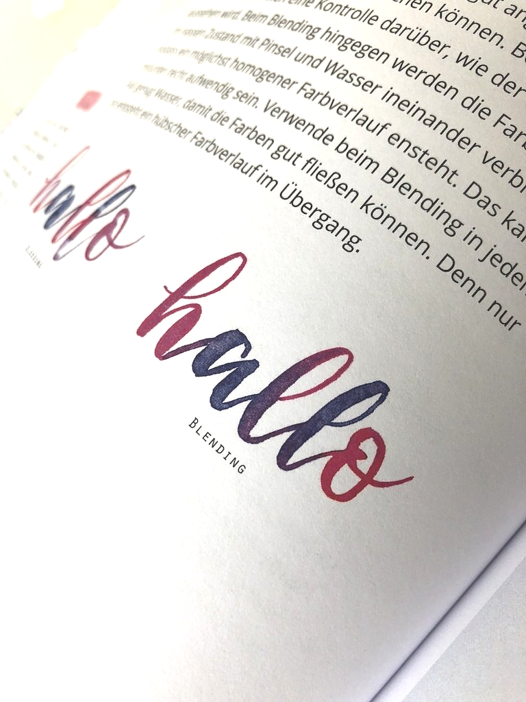 Das Wort Hallo ist mit einem Brushpen in der Farbe Lila handgezeichnet. Die Buchstaben des Wortes besitzen einen Farbverlauf, der von Lila bis Pink und Blau leuchtend strahlt.