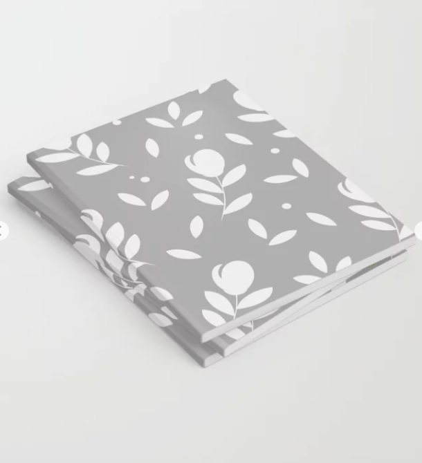 Notizbuch mit Blumen-Muster. Design und Produktmuster by Feinrosa. Die Grundfarbe ist ein helles Grau mit einem weißen Blumen-Muster verziert. Das Produktmuster stellt Tulpen mit zwei Blättern dar. Das Notizbuch ist bei Society6 erhältlich.