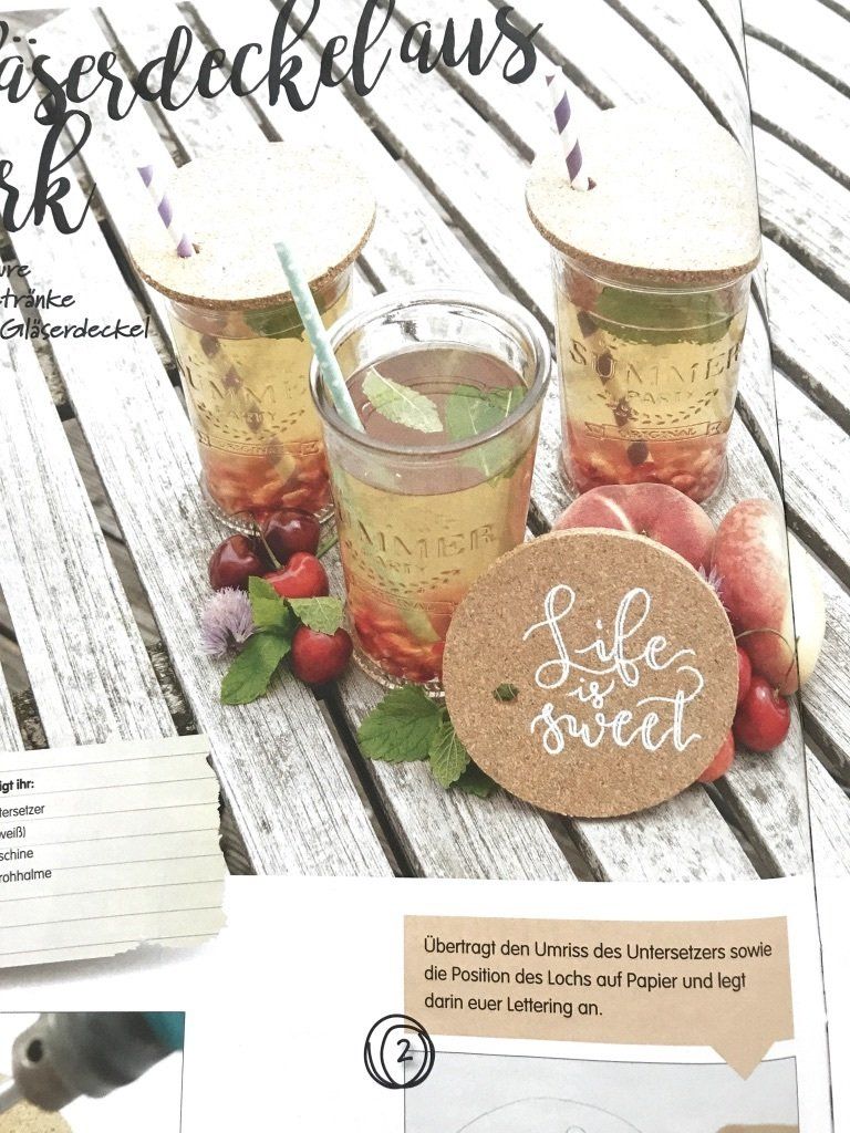 Gläser stehen auf einem Tisch. Gefüllt mit einem Getränk. Strohhalm steckt im Glas und vor den Gläsern liegt ein DIY-Korkdeckel, zum verschließen des Glases gegen z.B. Vespen und Co. Der Korkdeckel ist mit einem weißen Marker mit einem Handlettering verziert.