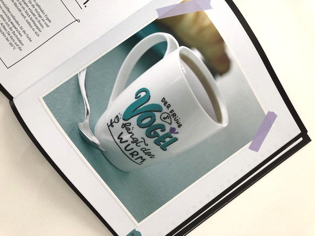 Handlettering auf einer Porzellan-Tasse. Der frühe Vogel fängt den Wurm.