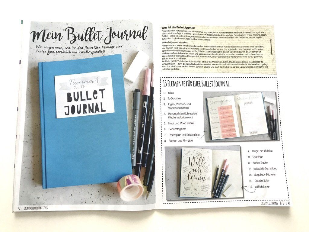 Blaues Bullet Journal Cover mit weißem Etikett und Handlettering-Beschriftung in schwarz. Daneben liegen Fineliner, Brushpens, Radiergummi und Washi Tape.