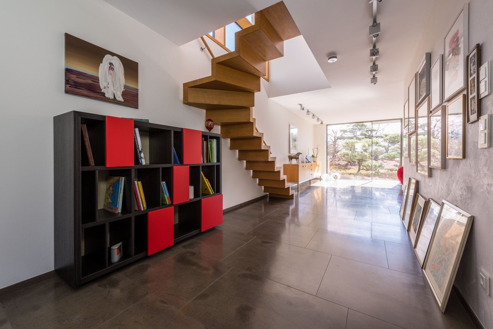 Ebenholz-Regal für das Wohnzimmer von Schreiner Bleier, rot und schwarz, Ansicht von der Seite im Raum, im Hintergrund eine Holztreppe