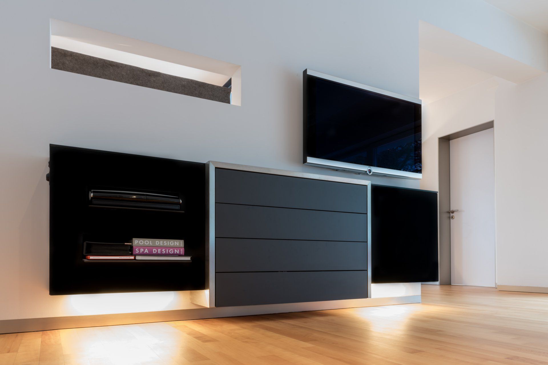 Wandhängendes Audio-Sideboard in Schwarz mit Edelstahl von Schreinerei BLEIER Lebensräume, sehr edel in einem hellen Wohnzimmer, mit TV darüber