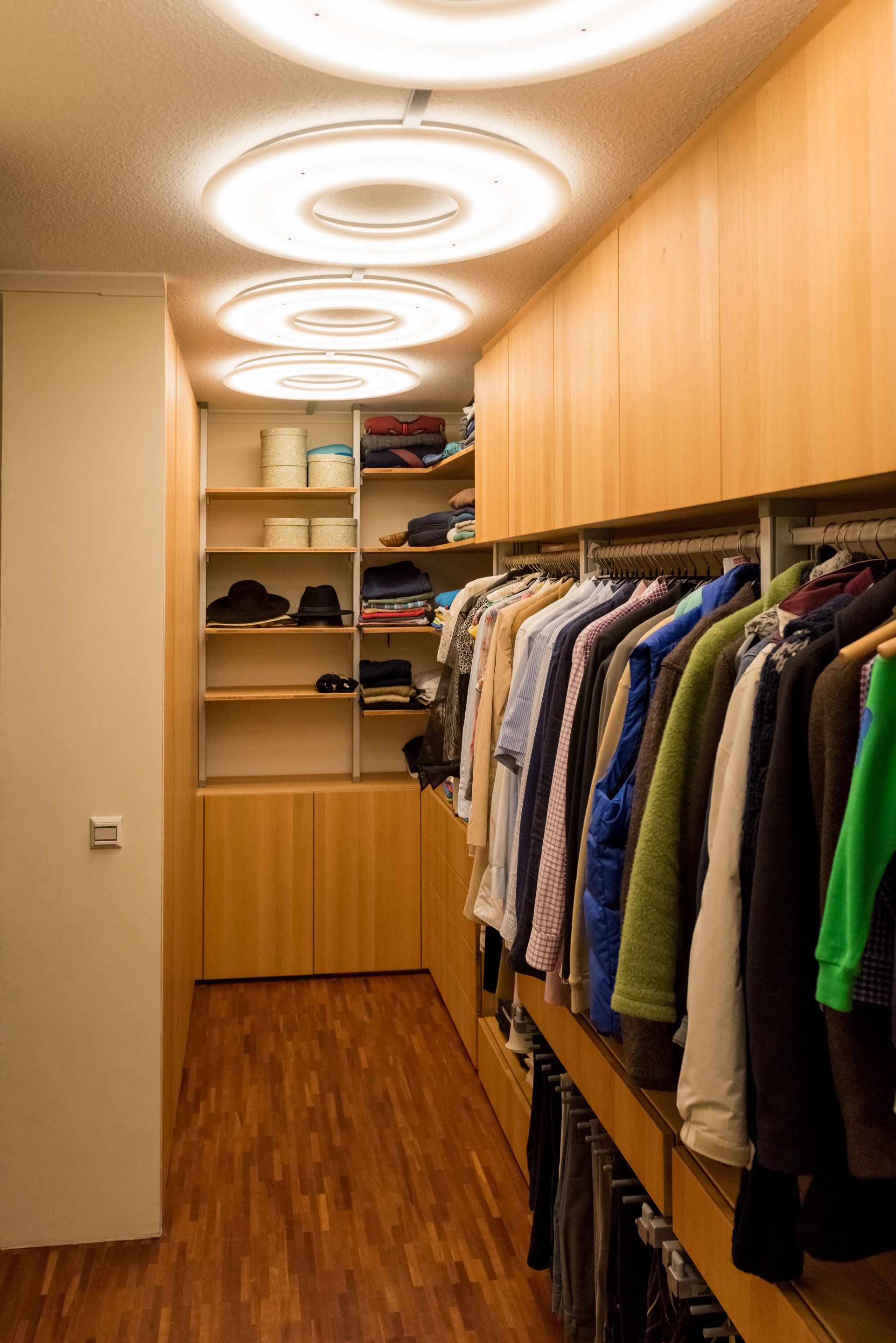 Begehbarer Kleiderschrank aus Erle Vollholz, geölt, von Schreinerei BLEIER Lebensräume, Schrank mit Deckenleuchten und Kleidung sowie Accessoires