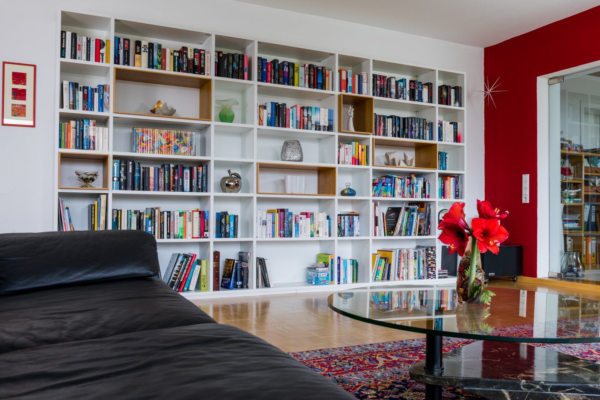 Wohnzimmer mit Bücherwand mit Einschubelementen aus Holz vom Schreiner