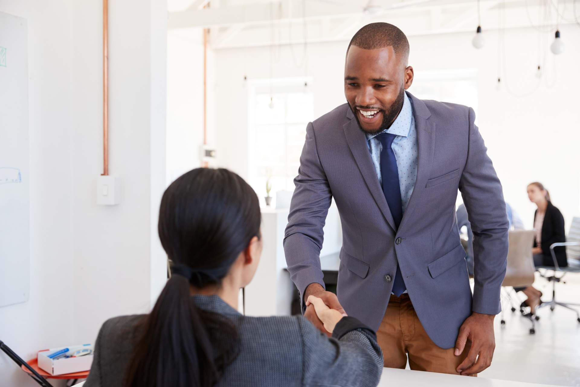 a man shaking hands with a woman sitting at a desk