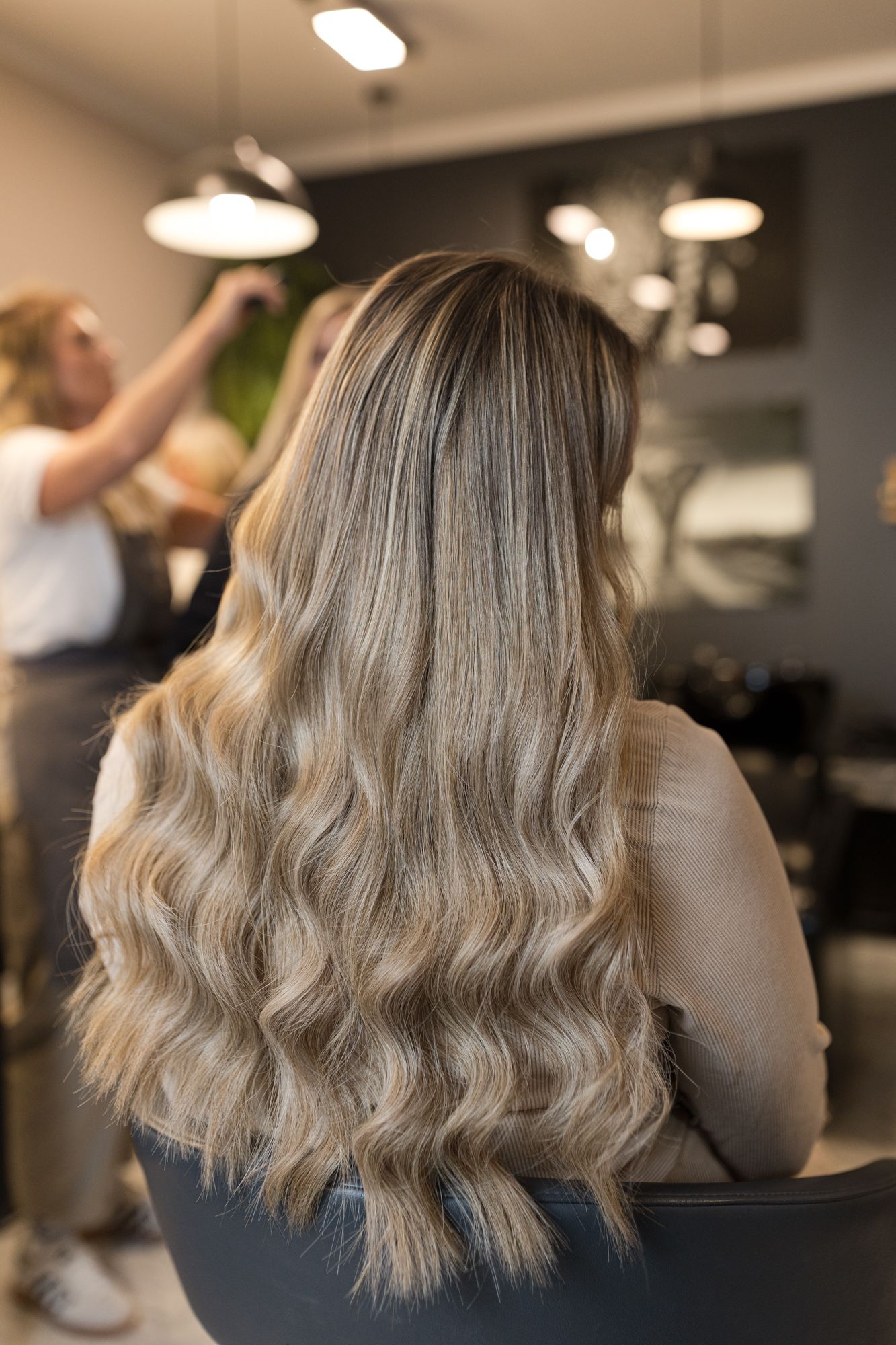 Vorher-Nachher-Vergleich einer Haarverdichtung mit weichen Wellen: mittellanges Haar zu vollerem, längerem Ergebnis.