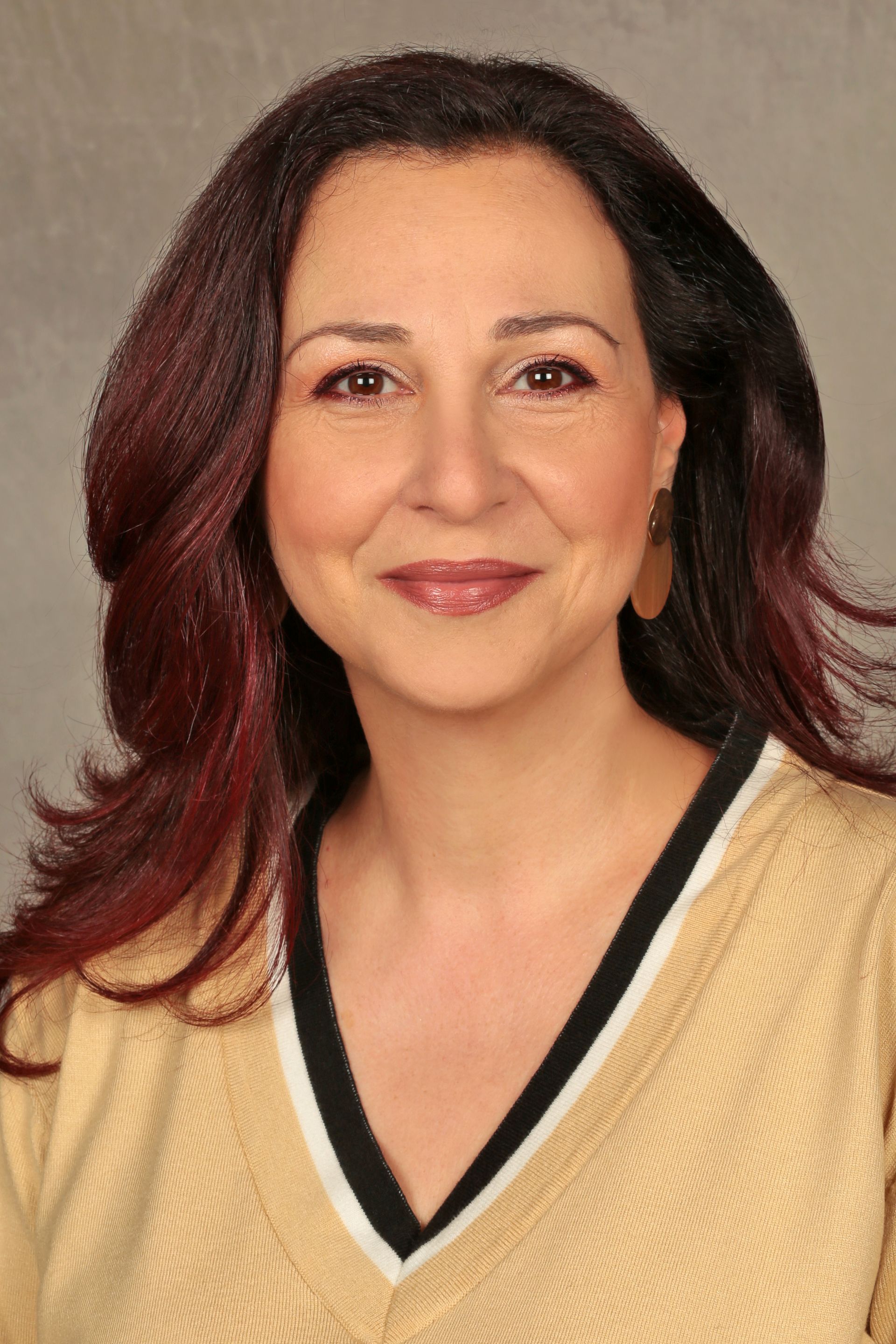 Lächelnde dunkelhaarige Frau mit langen Haaren, Beiger Pullover mit schwarzen Akzenten, V-Ausschnitt, beiger Hintergrund