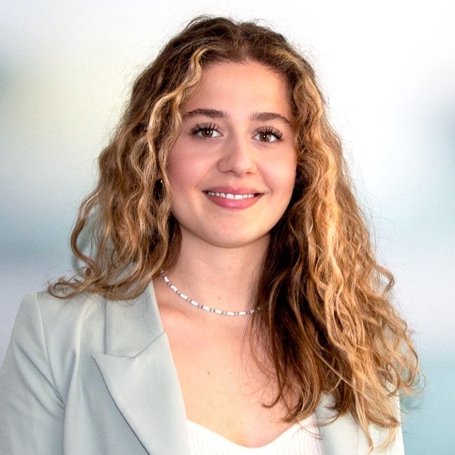 Lächelnde Frau. Blonde lockige Haare, Heller Blazer.