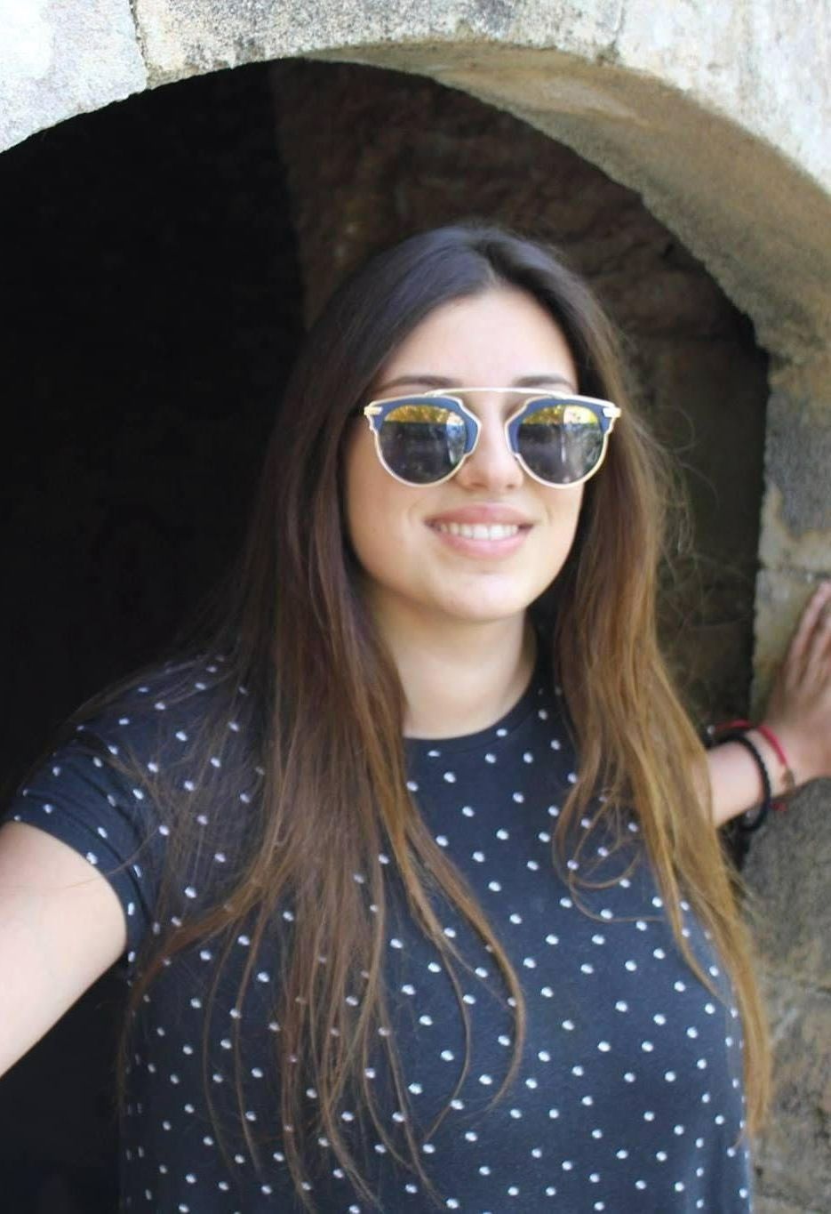 Lächelnde Frau mit Sonnenbrille und dunkelblauer gepunkteter Bluse