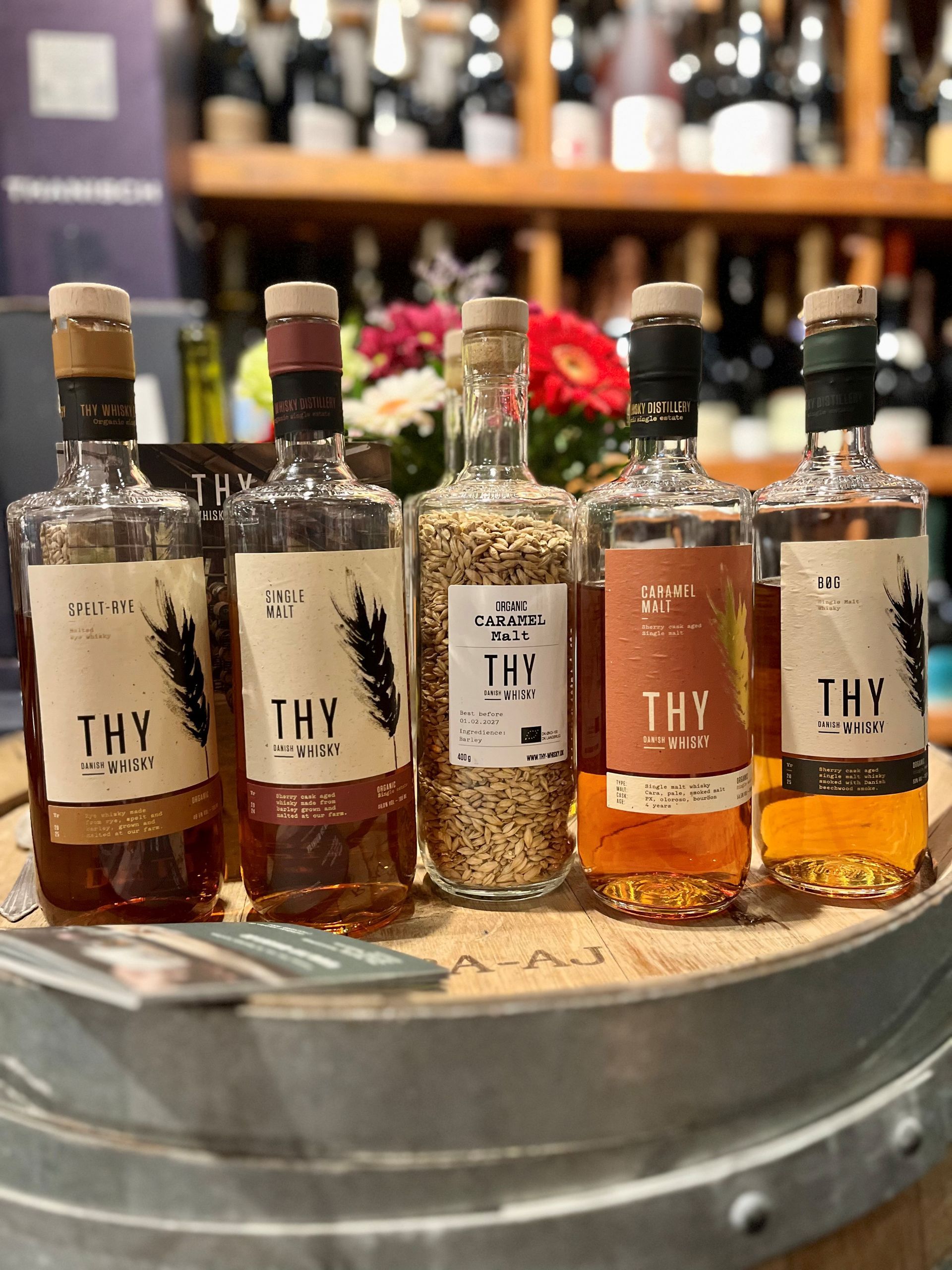 Eine Aufreihung von vier Flaschen Whisky und einer Flasche, die mit Getreide gefüllt ist.