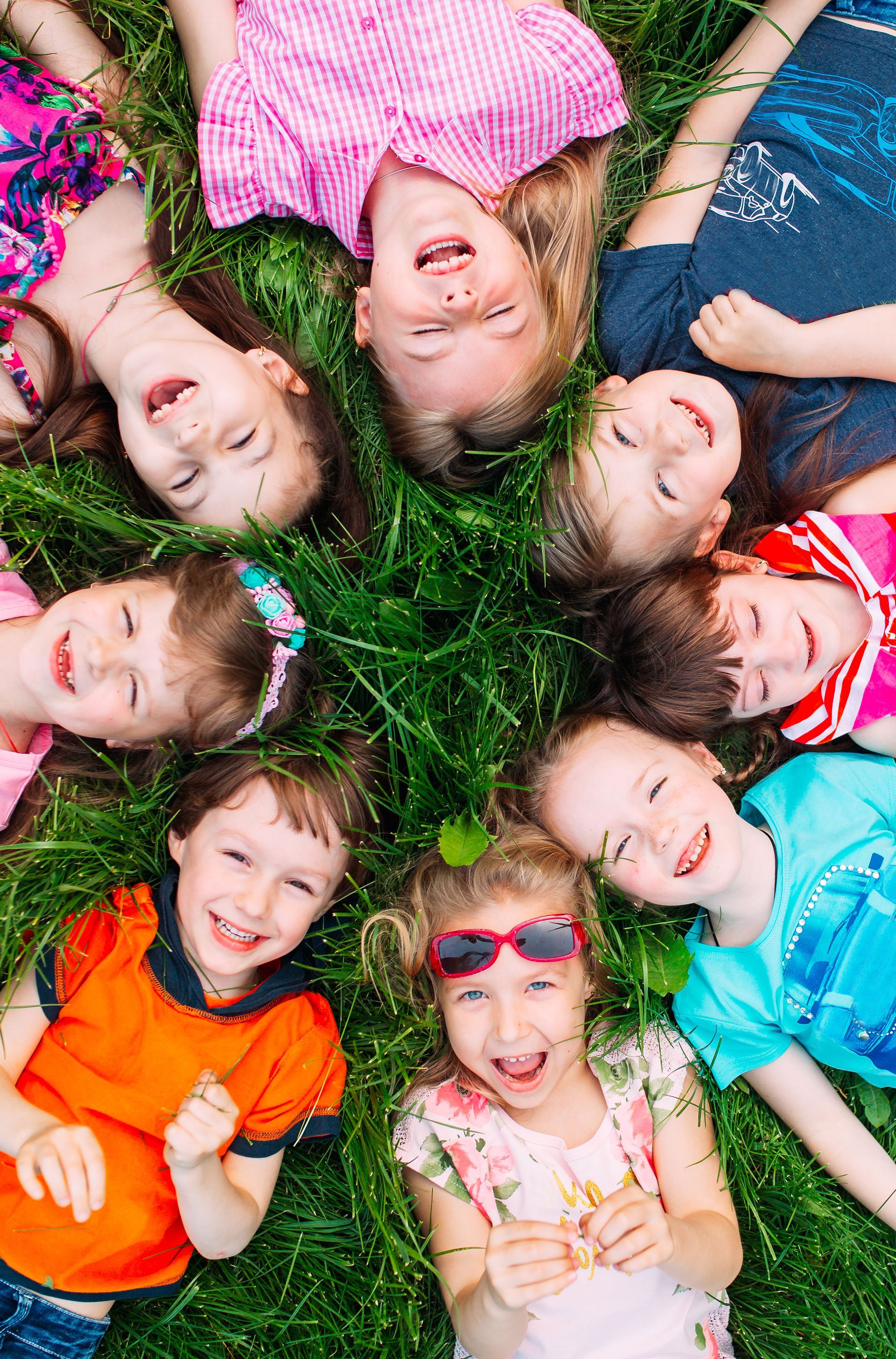 Kinder die auf dem Rasen liegen und glücklich sind