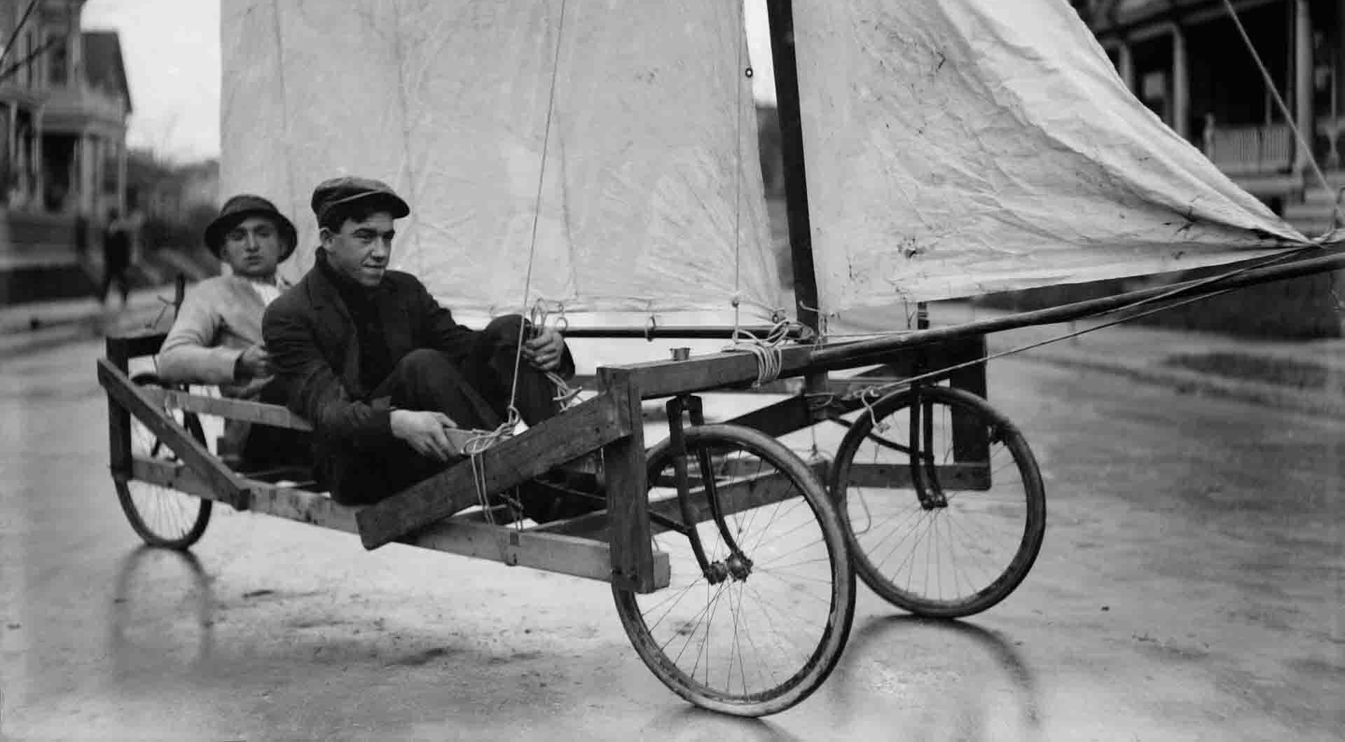 Windwagen um 1900 Bild in schwarz-weiß. Zwei Männer um Neunzehnhundert sitzen in einem Windwagen.