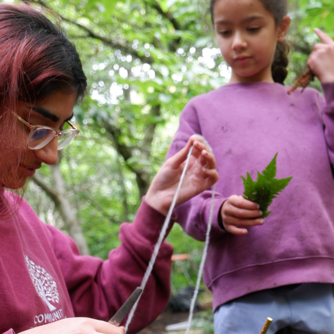 Amirah from Communitree with child making wand out of sticks and leaves