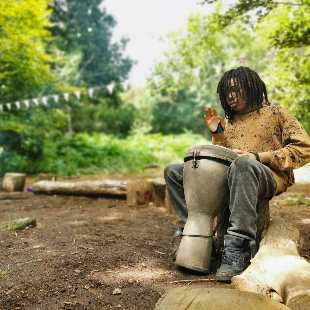 Child at the fire circle playing a drum