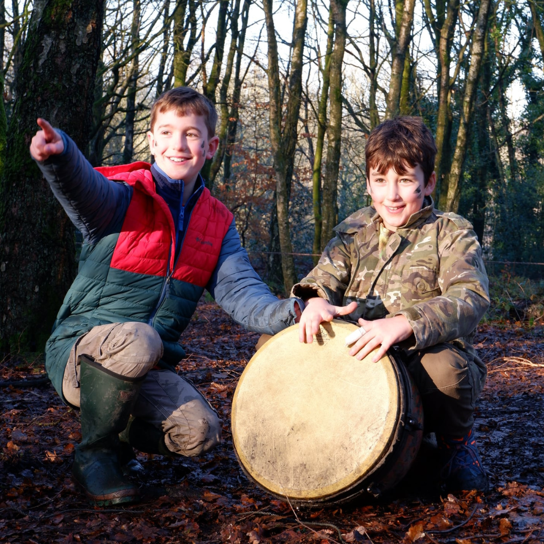 Two boys playing the drums in the woodland
